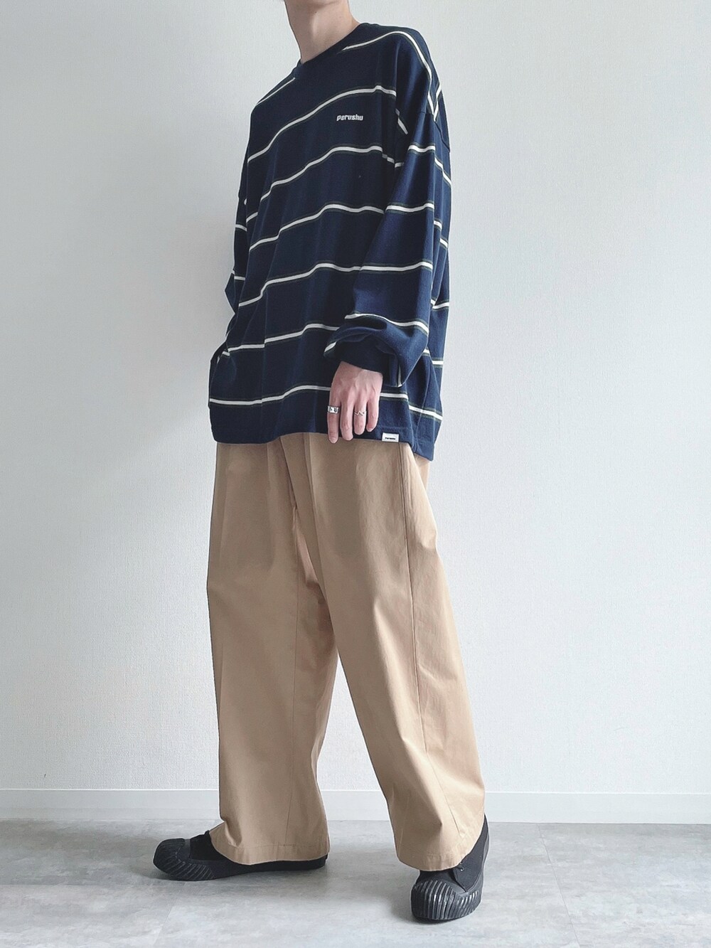 ブルー系のTシャツ/カットソー、ベージュ系のチノパンツ、ブラック系のスニーカーを着用したメンズの秋コーディネートの2枚目の写真