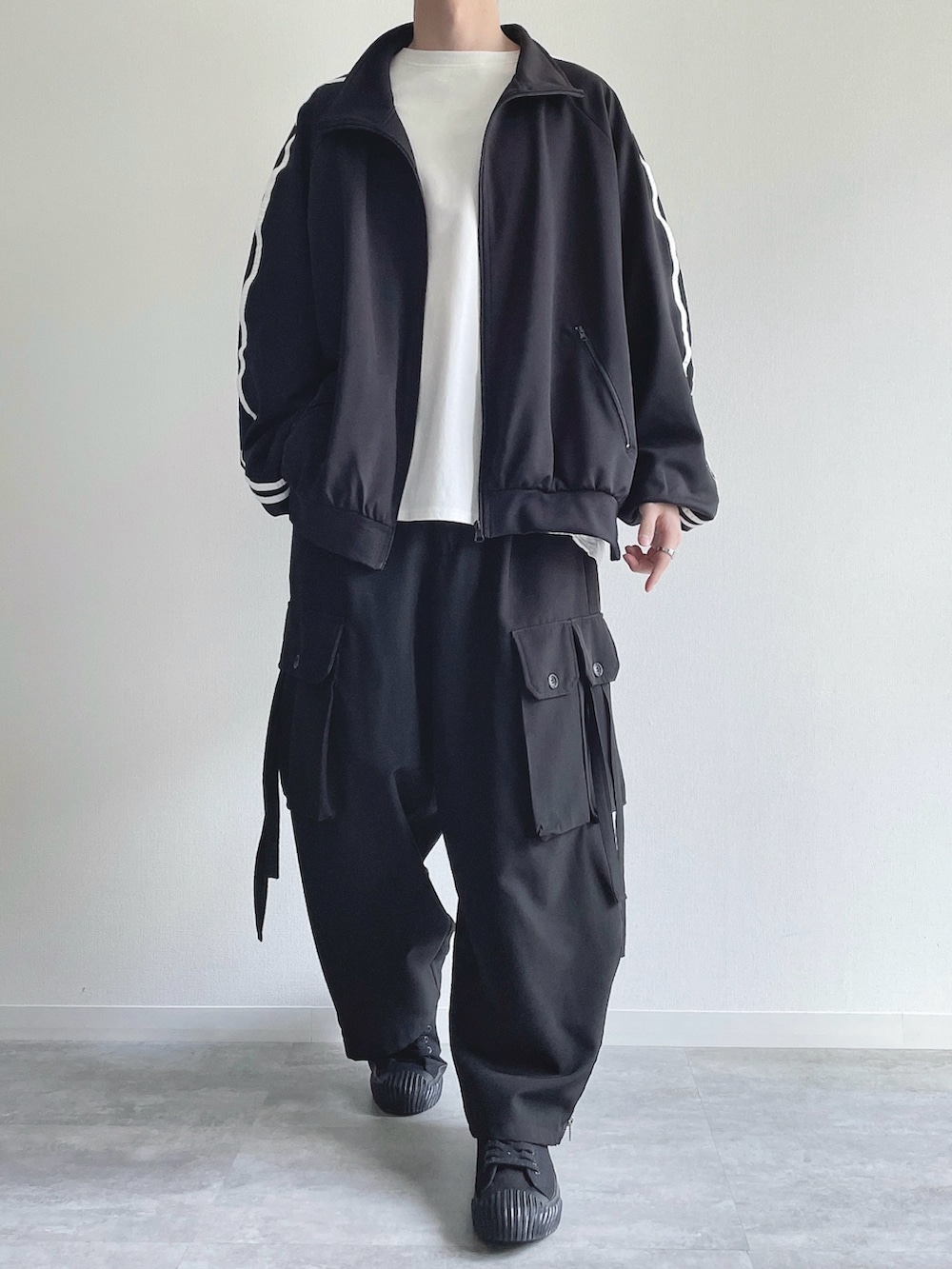 ブラック系のブルゾン、ホワイト系のTシャツ/カットソー、ブラック系のカーゴパンツを着用したメンズの春コーディネートの2枚目の写真