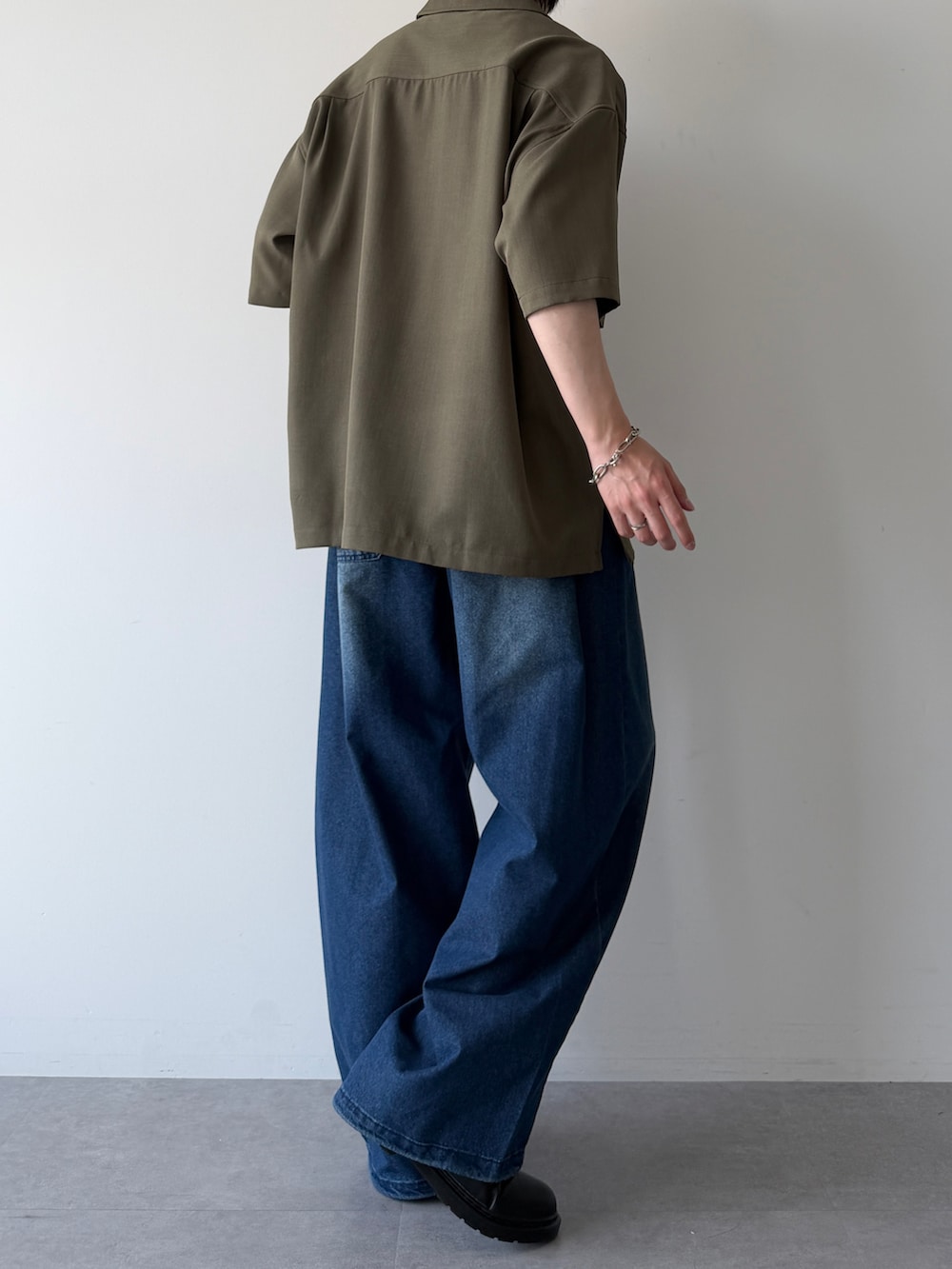 グリーン系のシャツ/ブラウス、ブルー系のデニムパンツ、ブラック系のシューズを着用したメンズの春コーディネートの4枚目の写真
