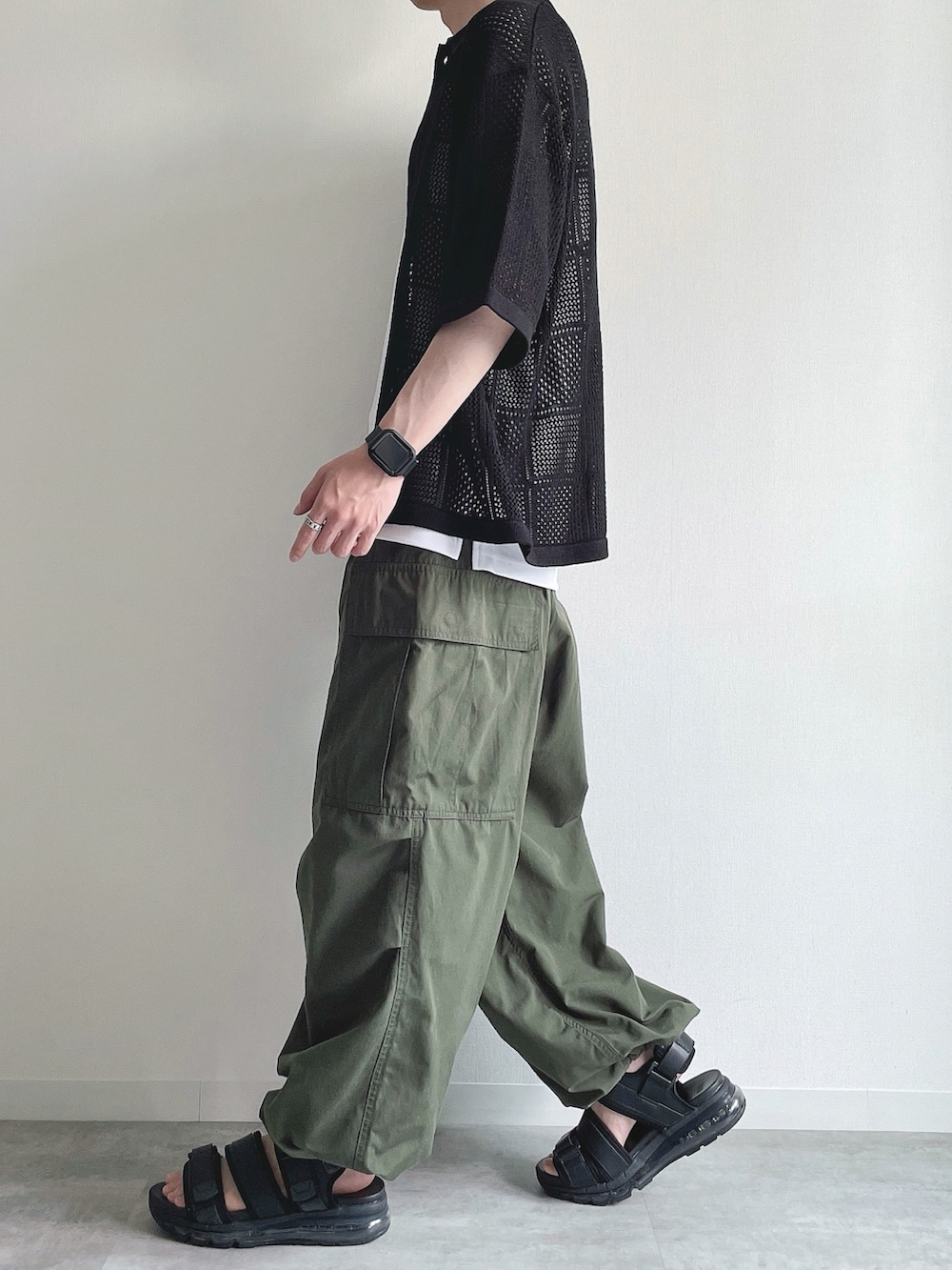 ブラック系のトップス、ホワイト系のタンクトップ、グリーン系のカーゴパンツを着用したメンズの春コーディネートの3枚目の写真