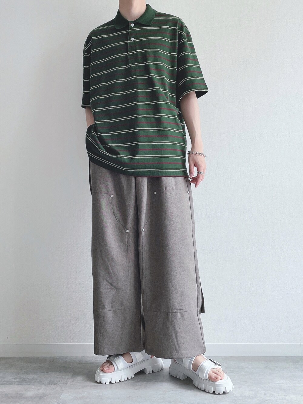 グリーン系のトップス、ベージュ系のスラックス、ホワイト系のサンダルを着用したメンズの夏コーディネートの2枚目の写真