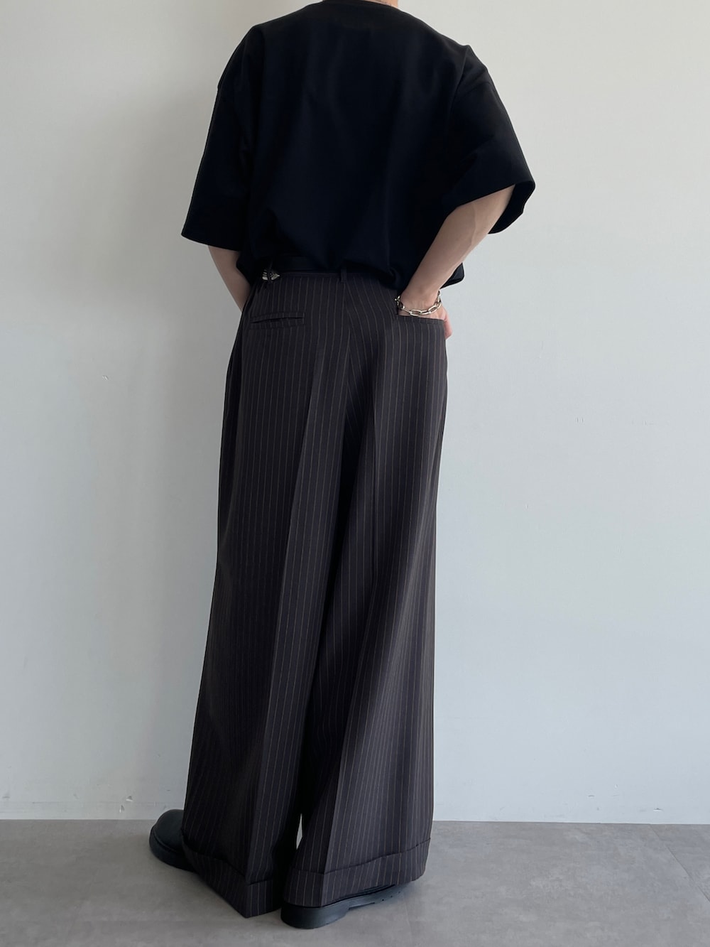 グレー系のスラックス、ブラック系のTシャツ/カットソー、ブラック系のシューズを着用したメンズの夏コーディネートの3枚目の写真