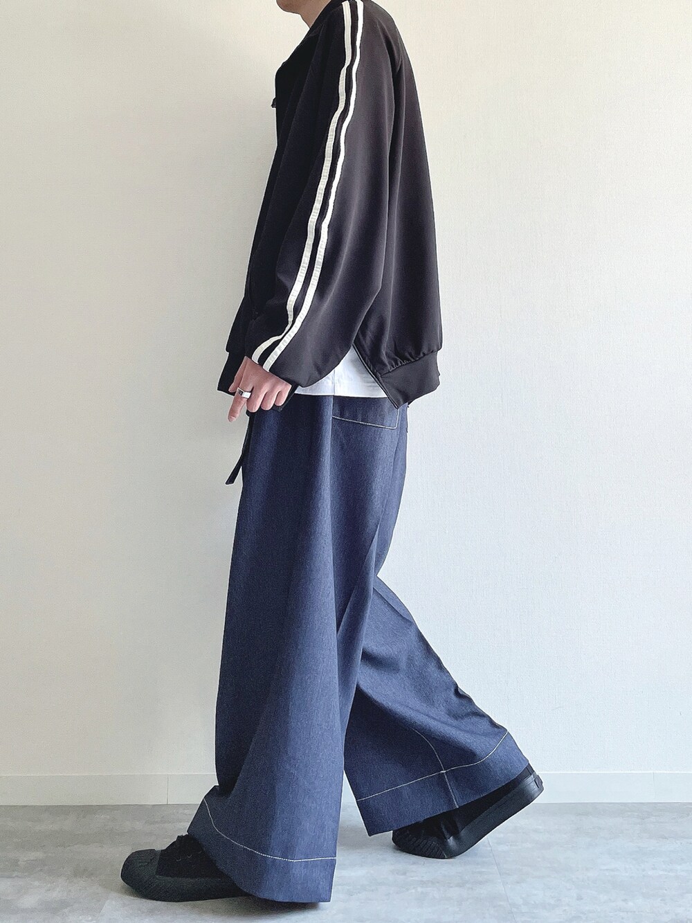ブラック系のブルゾン、ホワイト系のTシャツ/カットソー、ブルー系のデニムパンツを着用したメンズの春コーディネートの3枚目の写真