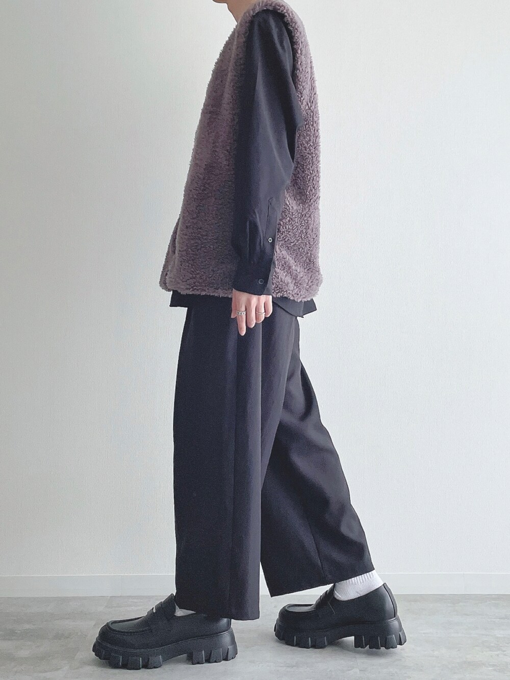 グレー系のベスト、ブラック系のトップス、ブラック系のスラックスを着用したメンズの秋コーディネートの2枚目の写真