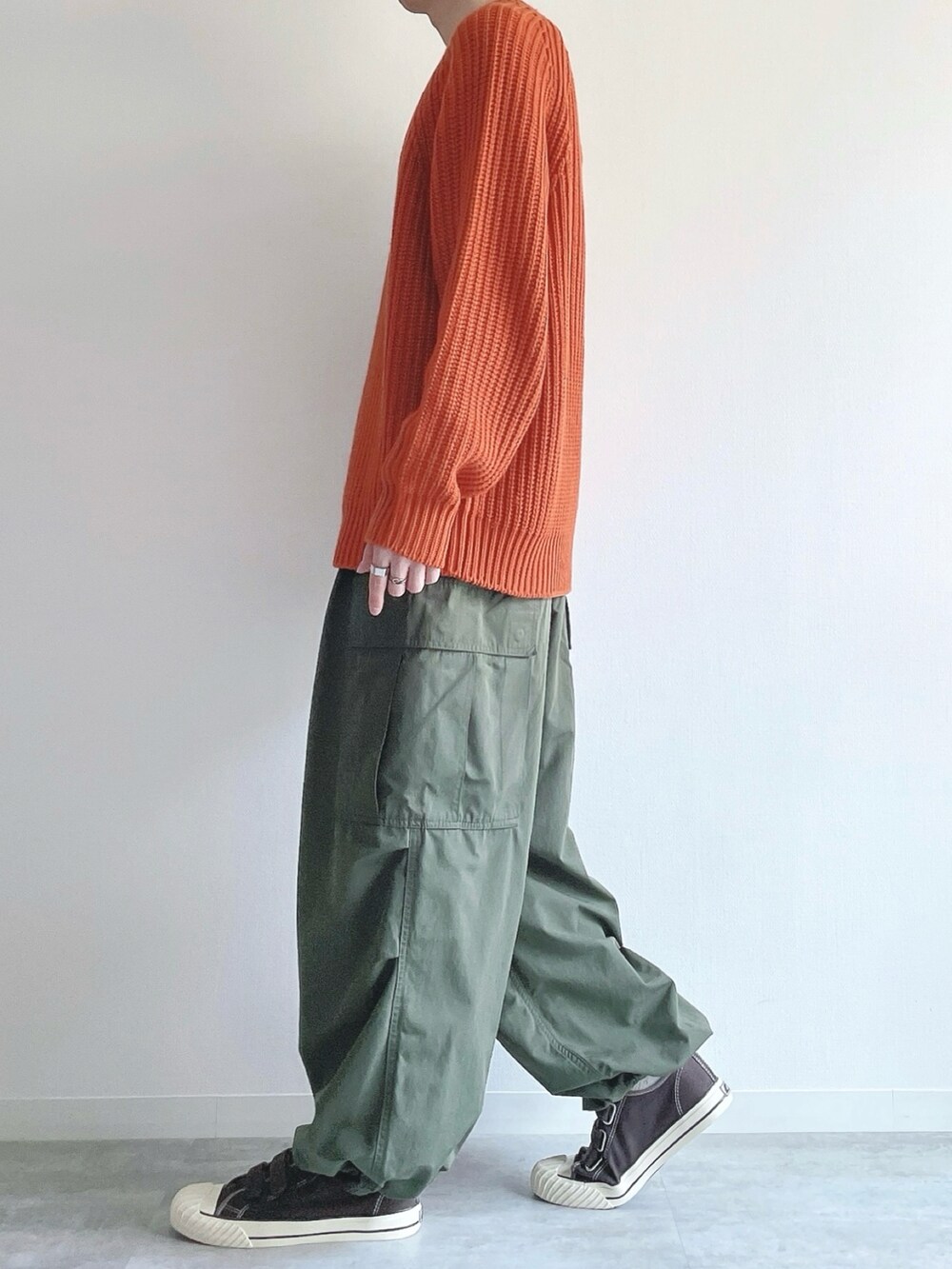 オレンジ系のトップス、グリーン系のカーゴパンツ、ブラウン系のスニーカーを着用したメンズの冬コーディネートの3枚目の写真