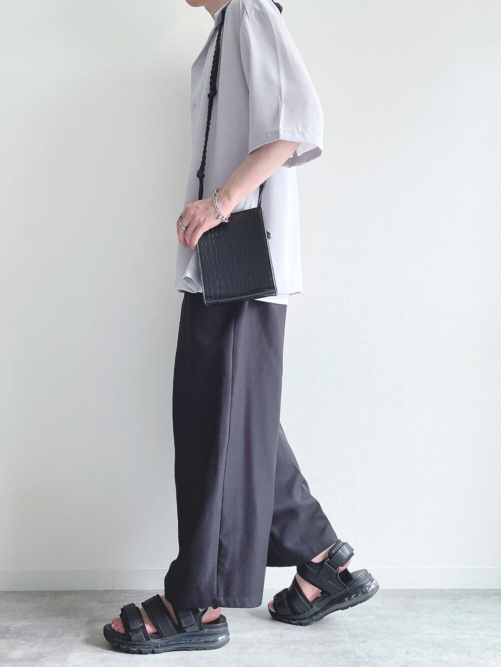 グレー系のトップス、ホワイト系のタンクトップ、ブラック系のスラックスを着用したメンズの夏コーディネートの3枚目の写真