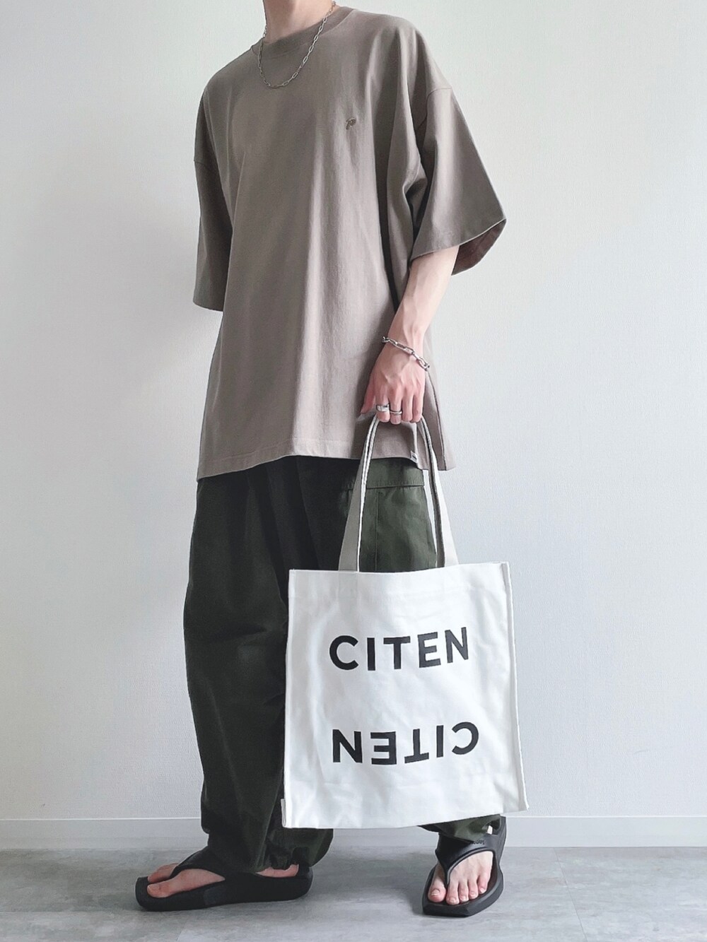 ベージュ系のTシャツ/カットソー、グリーン系のカーゴパンツ、ブラック系のサンダルを着用したメンズの夏コーディネートの4枚目の写真