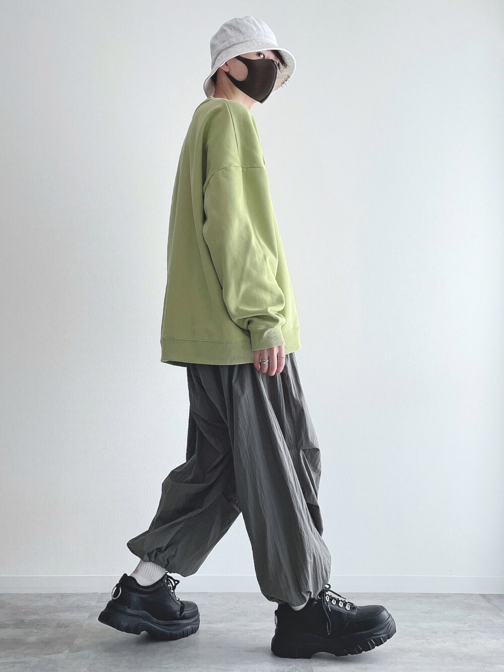 グリーン系のスウェット、グレー系のその他パンツ、ブラック系のスニーカーを着用したメンズの春コーディネートの2枚目の写真