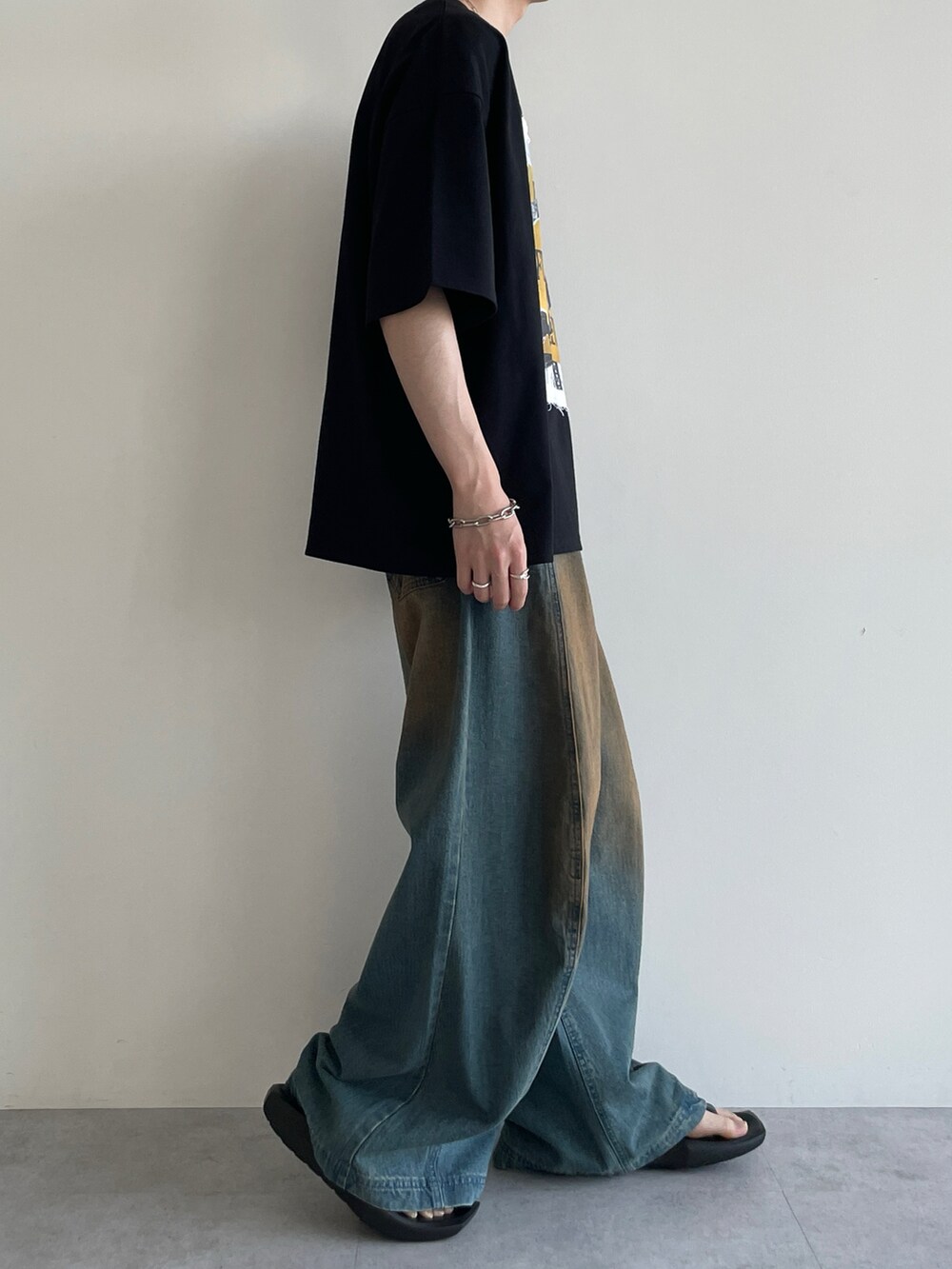 ブラック系のTシャツ/カットソー、ブルー系のデニムパンツ、ブラック系のサンダルを着用したメンズの夏コーディネートの3枚目の写真