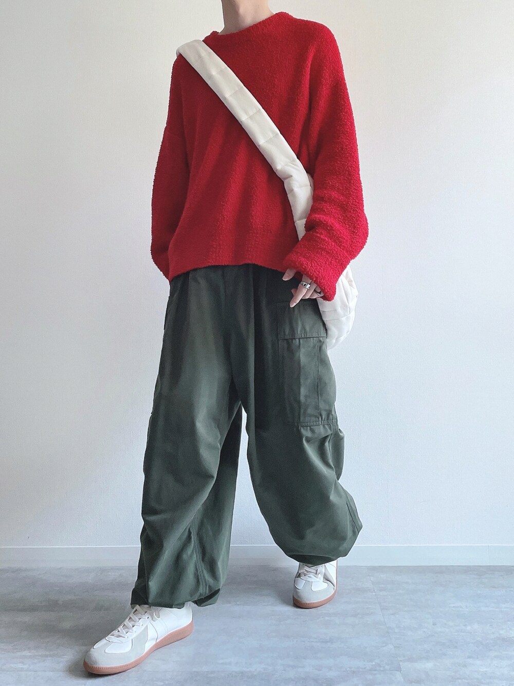 レッド系のニット/セーター、グリーン系のカーゴパンツ、ホワイト系のスニーカーを着用したメンズの冬コーディネートの5枚目の写真