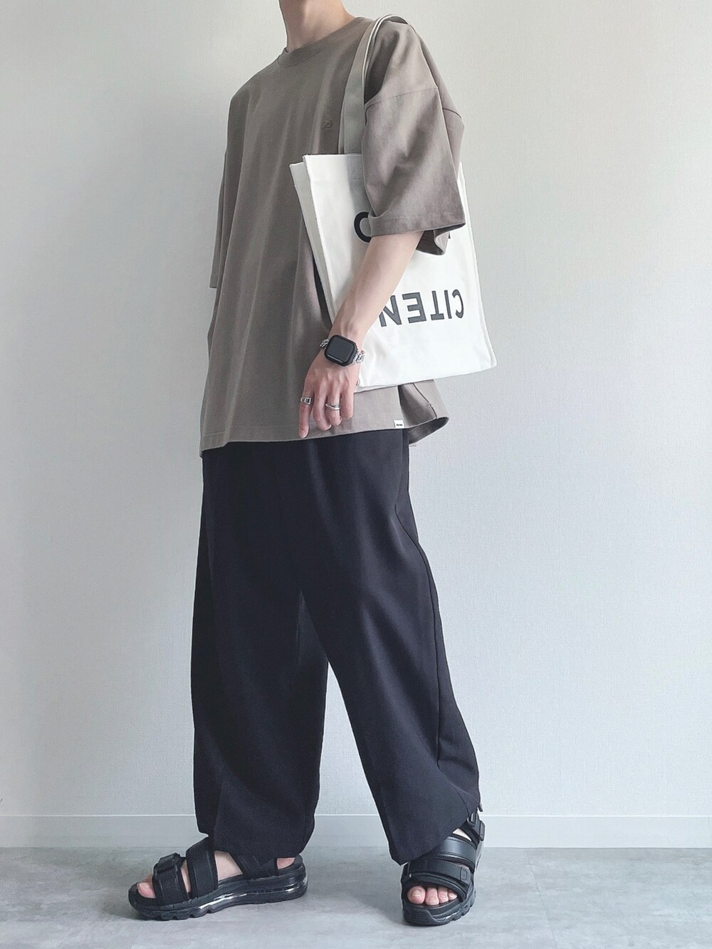 ベージュ系のTシャツ/カットソー、ブラック系のスラックス、ブラック系のサンダルを着用したメンズの夏コーディネートの2枚目の写真