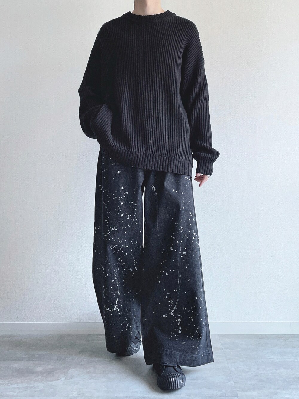 ブラック系のニット/セーター、ブラック系のデニムパンツ、ブラック系のスニーカーを着用したメンズの春コーディネートの2枚目の写真