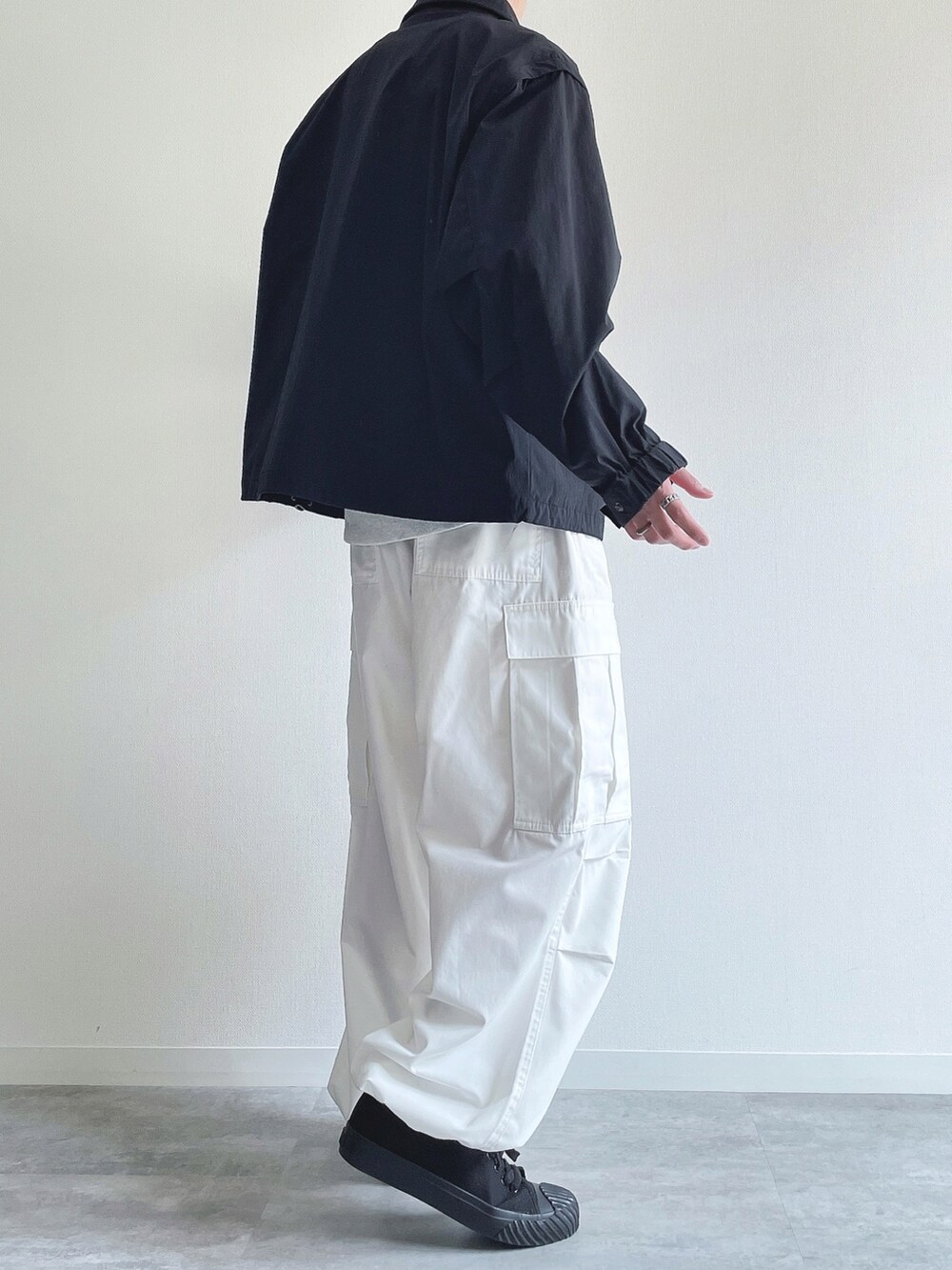 ブラック系のブルゾン、グレー系のトップス、ホワイト系のパンツを着用したメンズの春コーディネートの4枚目の写真