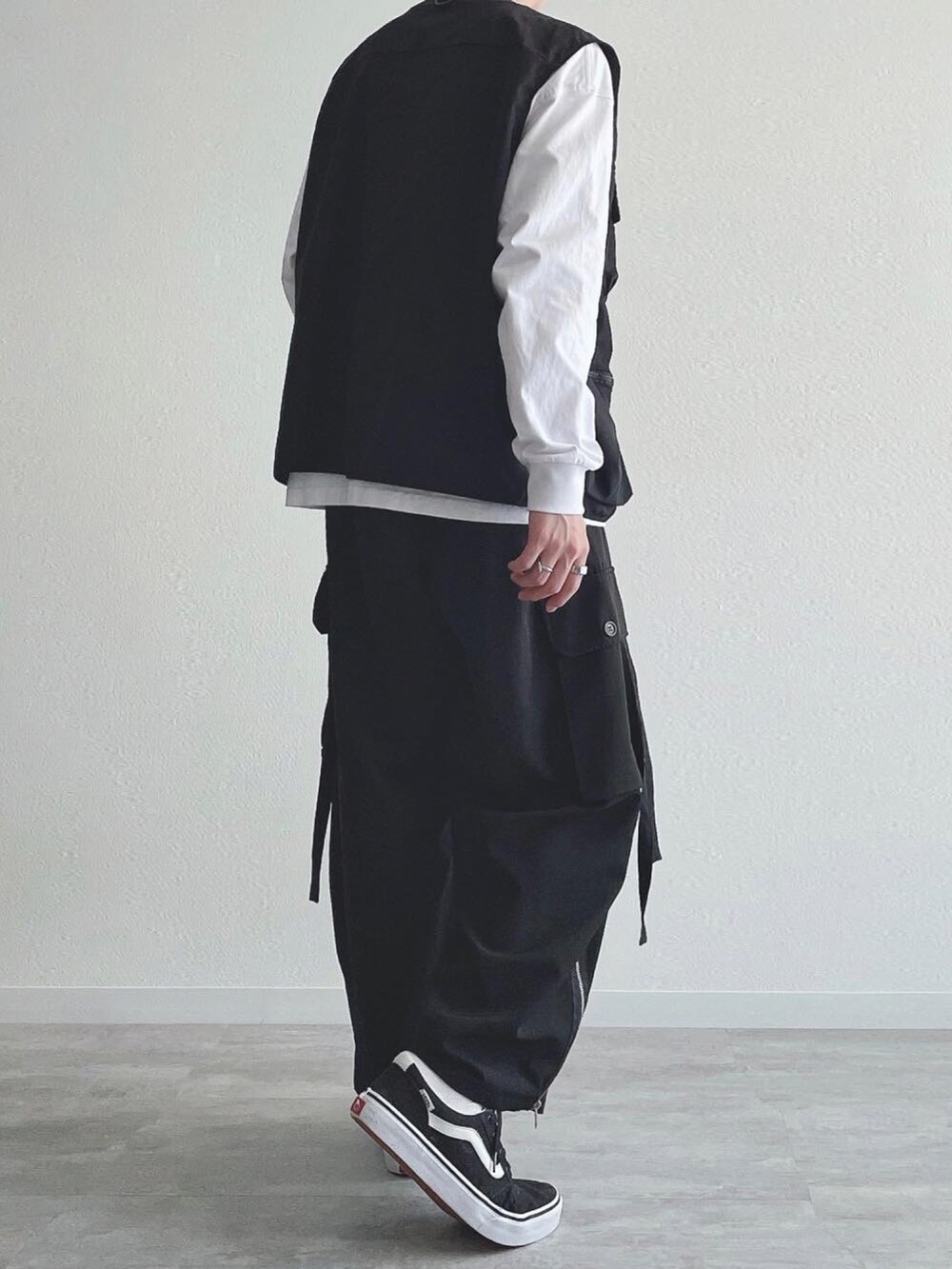 ブラック系のベスト、ホワイト系のTシャツ/カットソー、ブラック系のカーゴパンツを着用したメンズの秋コーディネートの4枚目の写真