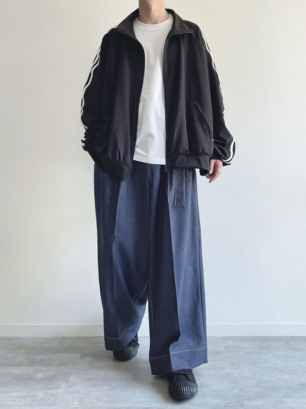 ブラック系のブルゾン、ホワイト系のTシャツ/カットソー、ブルー系のデニムパンツを着用したメンズの春コーディネートの2枚目の写真