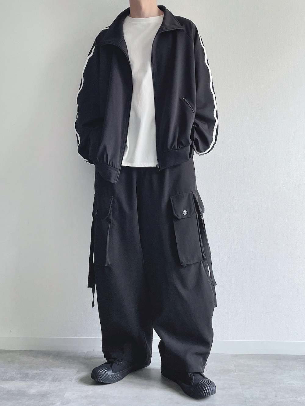 ブラック系のブルゾン、ホワイト系のTシャツ/カットソー、ブラック系のカーゴパンツを着用したメンズの春コーディネートの5枚目の写真