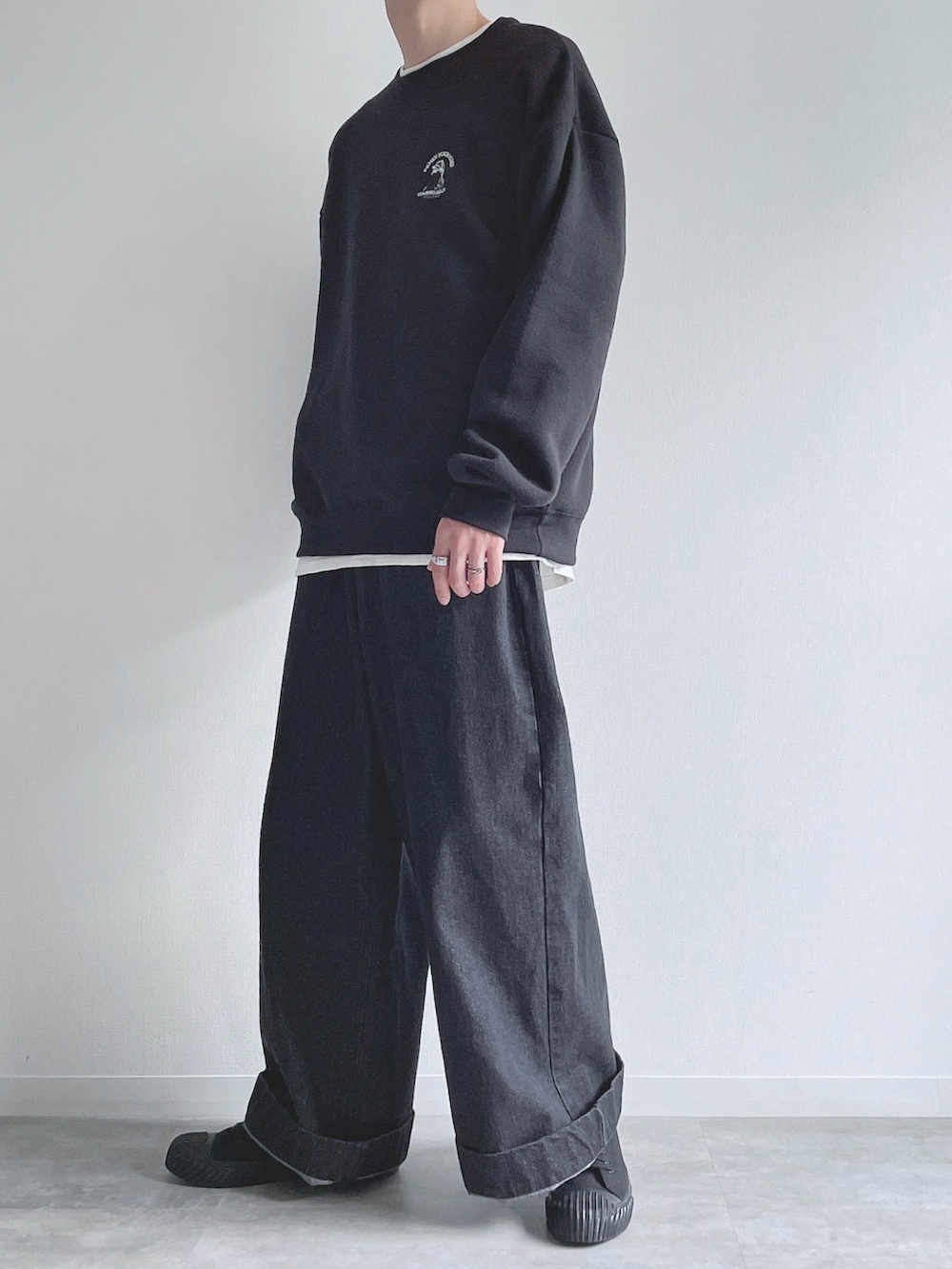 ブラック系のスウェット、ホワイト系のTシャツ/カットソー、ブラック系のデニムパンツを着用したメンズの冬コーディネートの4枚目の写真