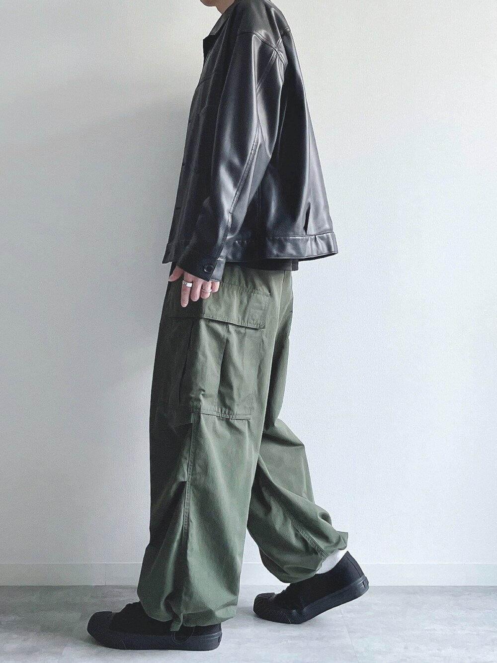 ブラック系のブルゾン、ブラック系のTシャツ/カットソー、グリーン系のカーゴパンツを着用したメンズの秋コーディネートの3枚目の写真