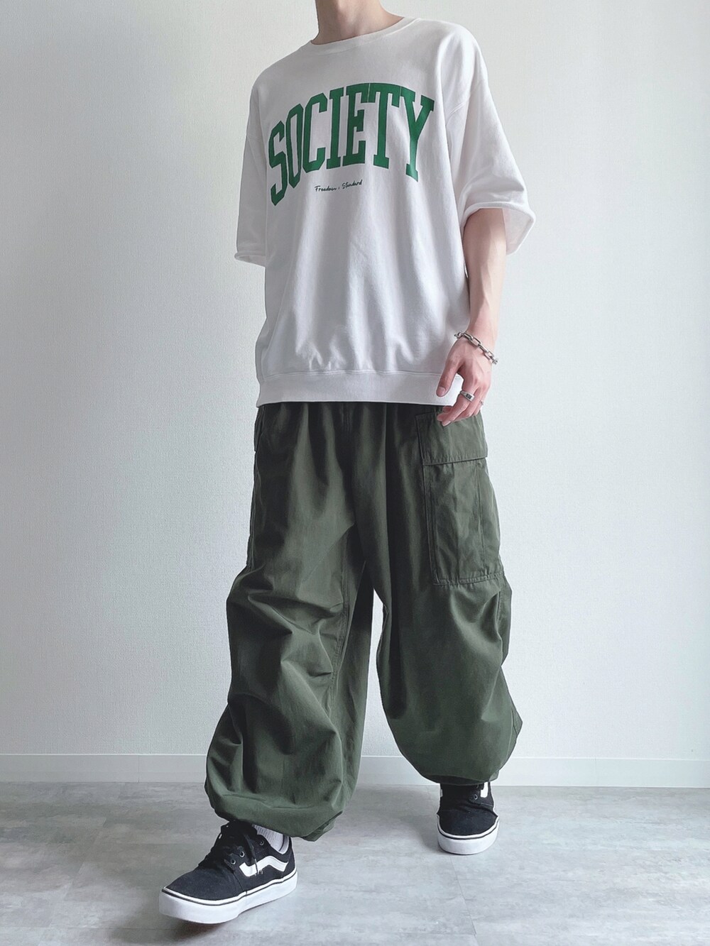 ホワイト系のTシャツ/カットソー、グリーン系のカーゴパンツ、ブラック系のスニーカーを着用したメンズの夏コーディネートの5枚目の写真