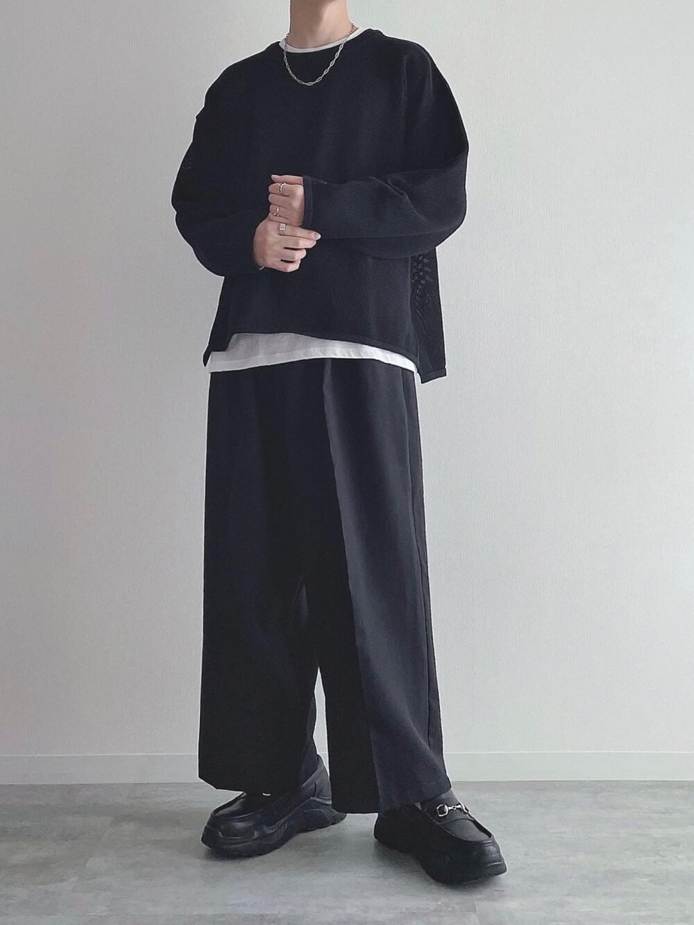 ブラック系のトップス、ブラック系のスラックス、ブラック系のスニーカーを着用したメンズの秋コーディネートの2枚目の写真