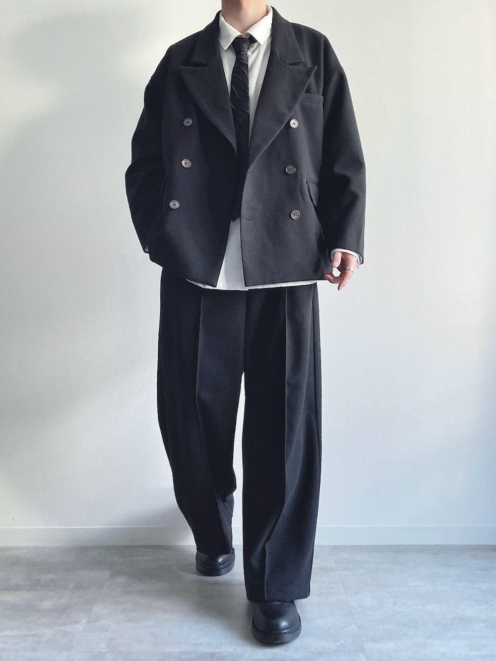 ブラック系のテーラードジャケット、ホワイト系のシャツ/ブラウス、ブラック系のスラックスを着用したメンズの冬コーディネートの2枚目の写真
