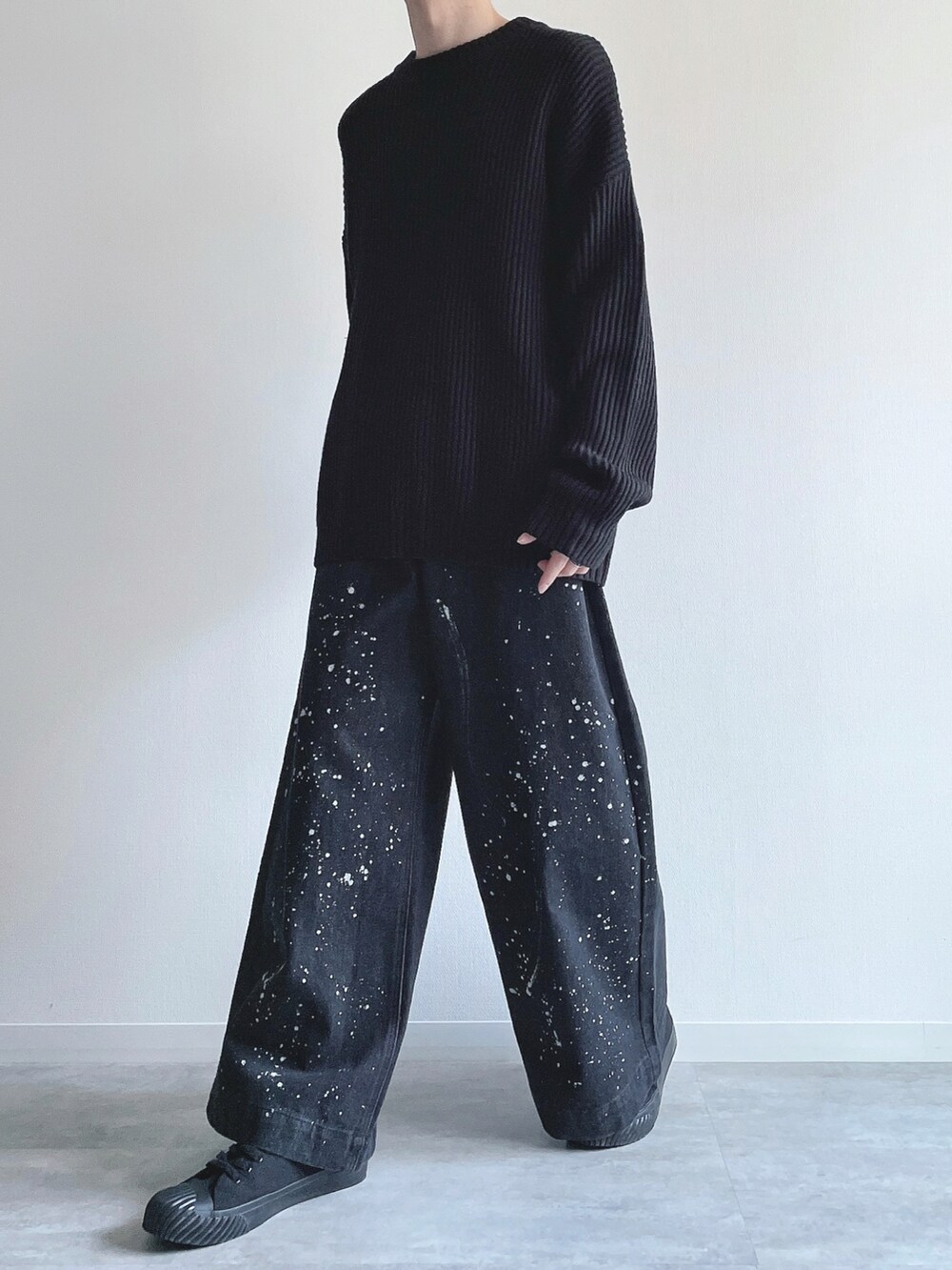 ブラック系のニット/セーター、ブラック系のデニムパンツ、ブラック系のスニーカーを着用したメンズの春コーディネートの5枚目の写真