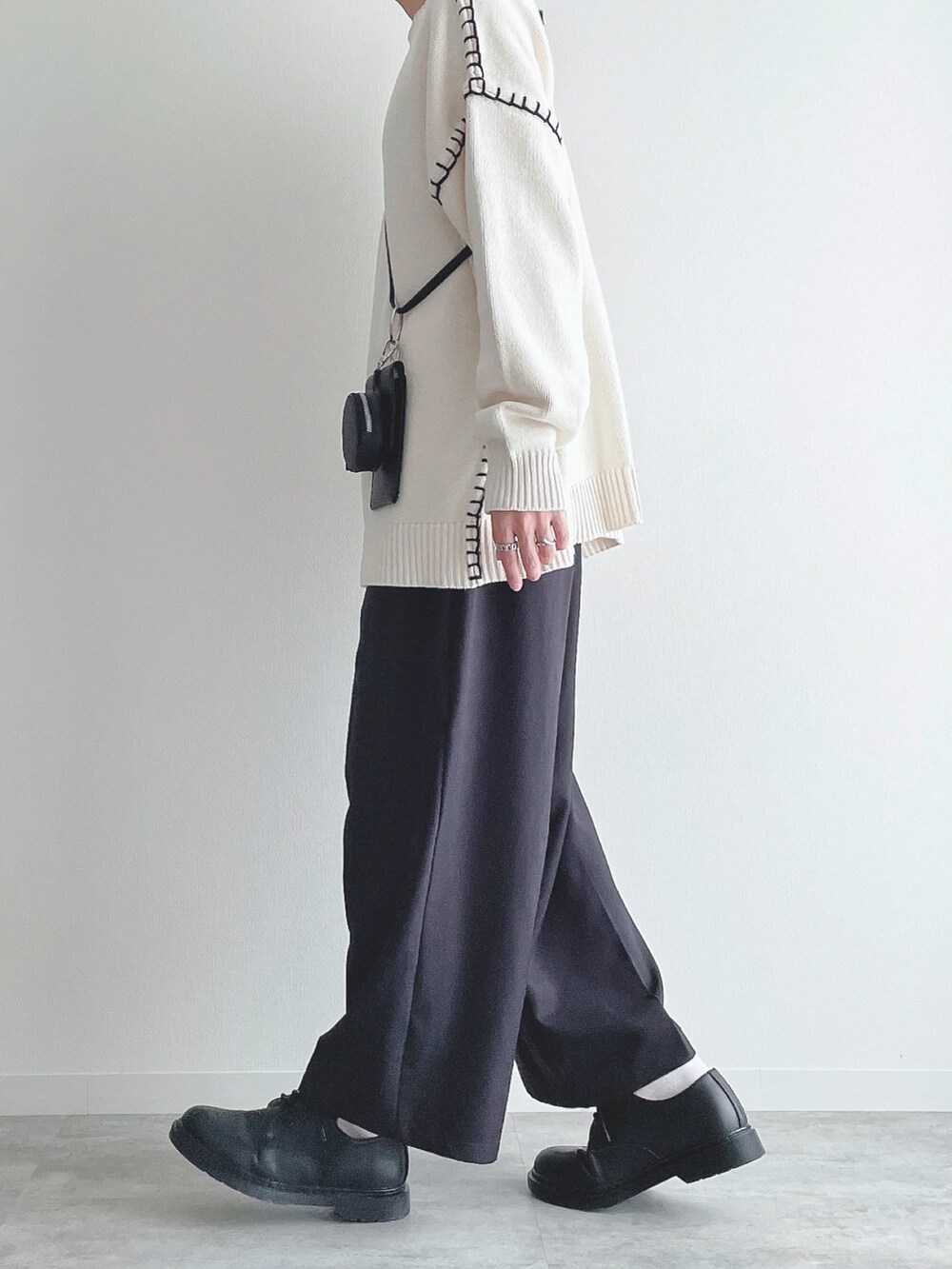 ホワイト系のニット/セーター、ブラック系のスラックス、ブラック系のドレスシューズを着用したメンズの秋コーディネートの2枚目の写真