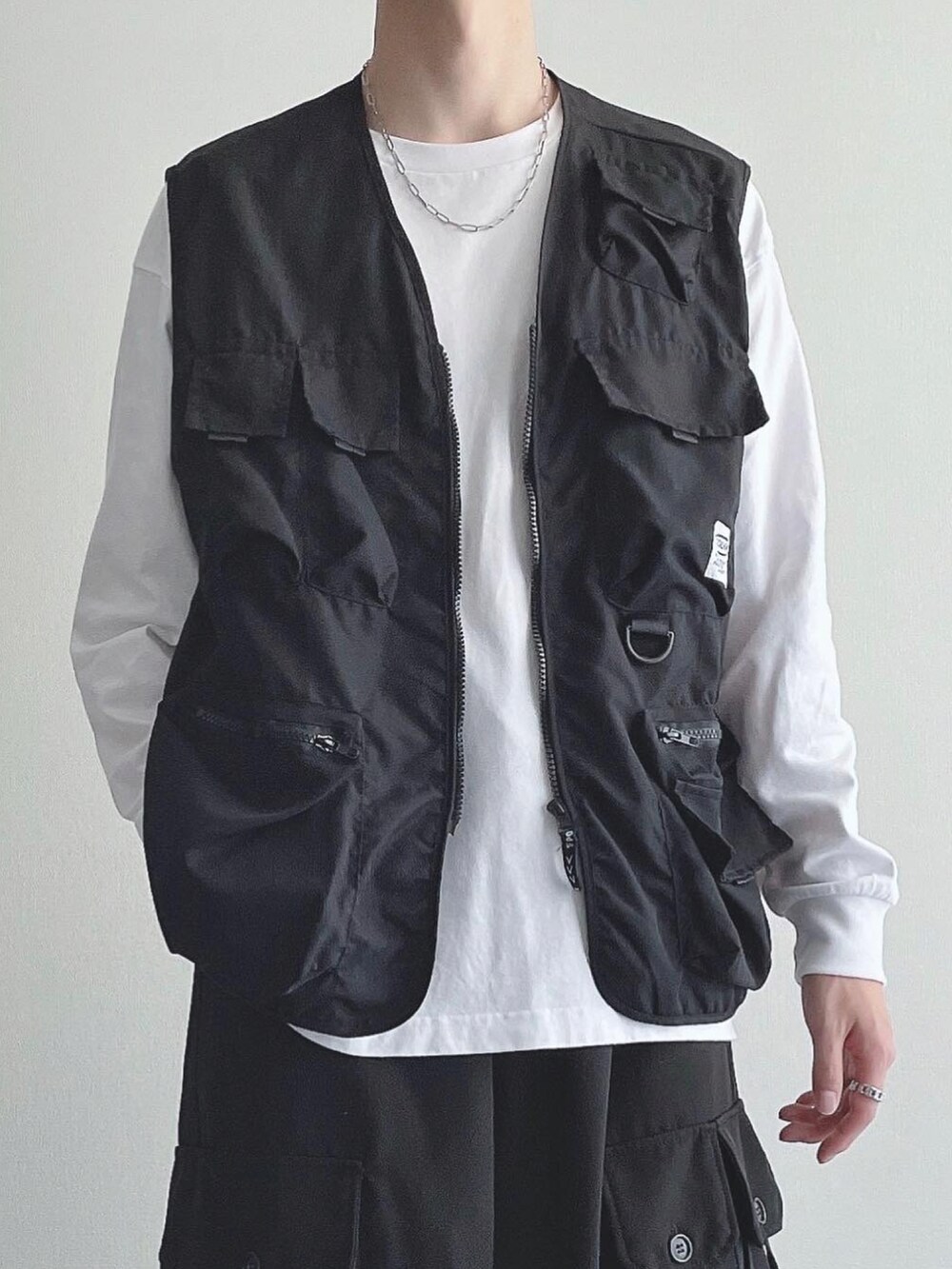 ブラック系のベスト、ホワイト系のTシャツ/カットソー、ブラック系のカーゴパンツを着用したメンズの秋コーディネートの3枚目の写真