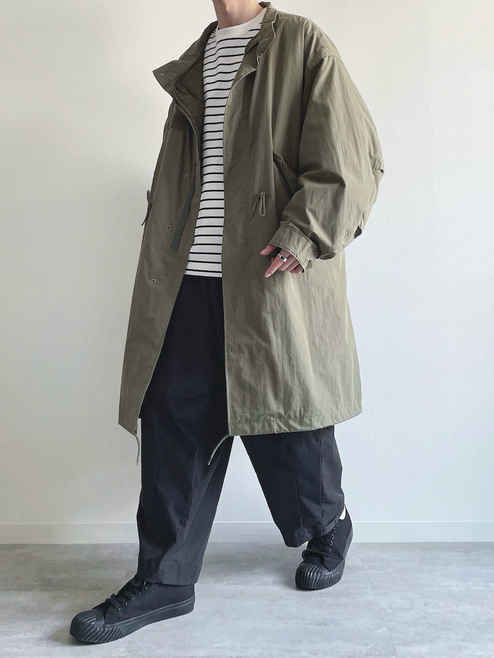 グリーン系のモッズコート、ホワイト系のTシャツ/カットソー、ブラック系のカーゴパンツを着用したメンズの春コーディネートの5枚目の写真