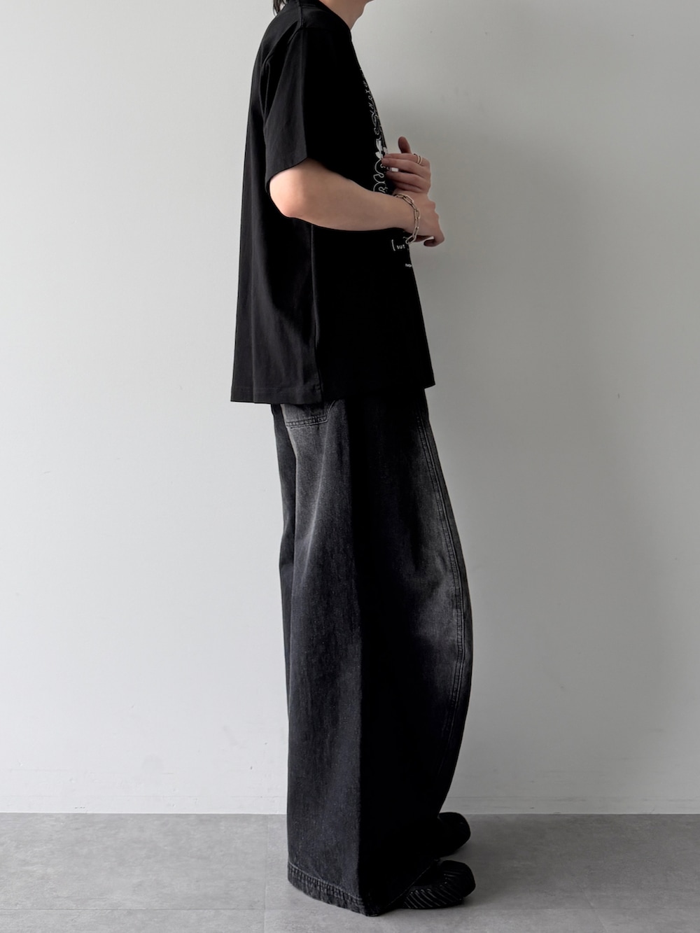 ブラック系のデニムパンツ、ブラック系のTシャツ/カットソー、ブラック系のスニーカーを着用したメンズの春コーディネートの3枚目の写真