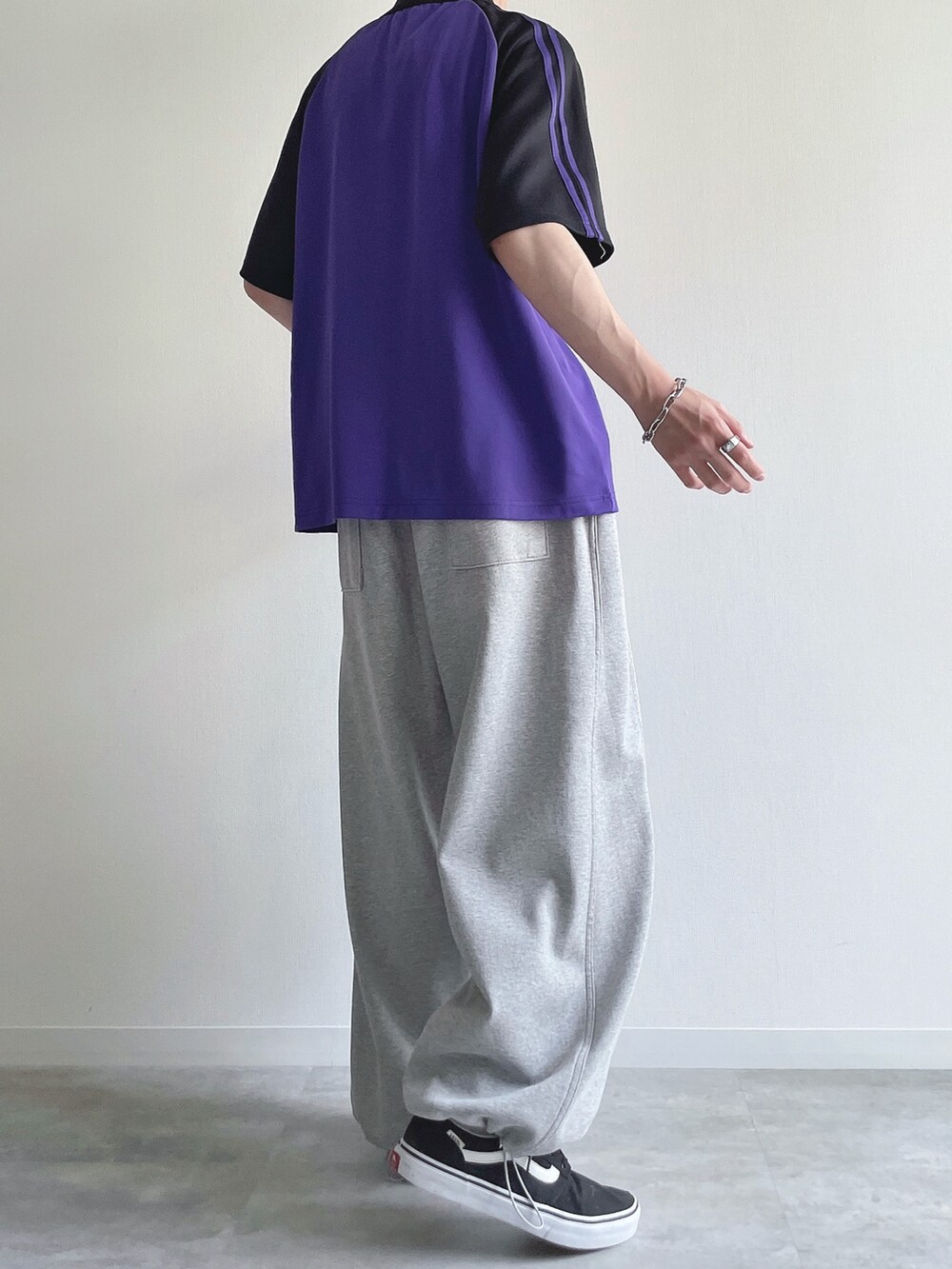 パープル系のTシャツ/カットソー、グレー系のパンツ、ブラック系のスニーカーを着用したメンズの秋コーディネートの4枚目の写真