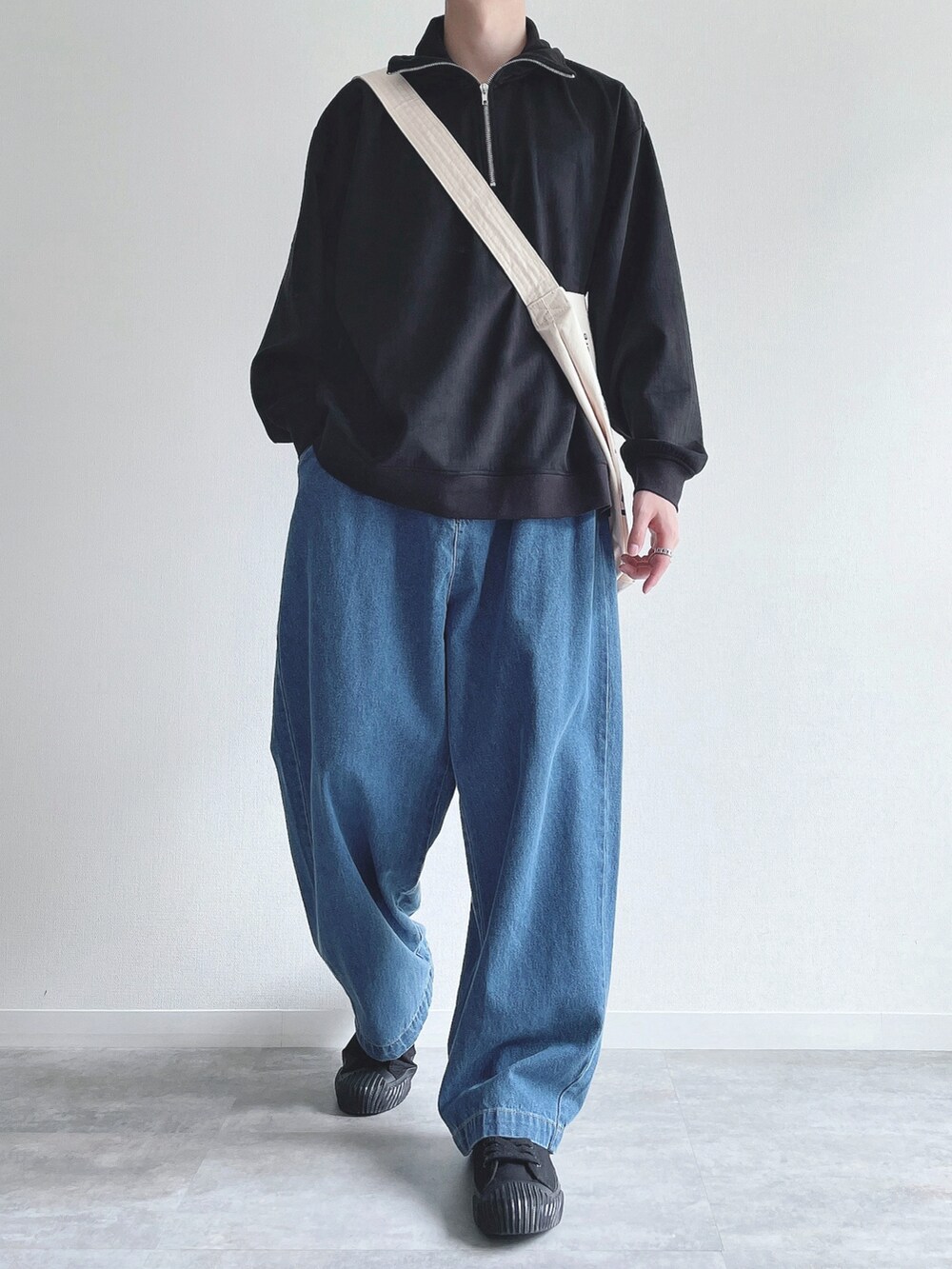 ブラック系のスウェット、ブルー系のデニムパンツ、ブラック系のスニーカーを着用したメンズの秋コーディネートの2枚目の写真