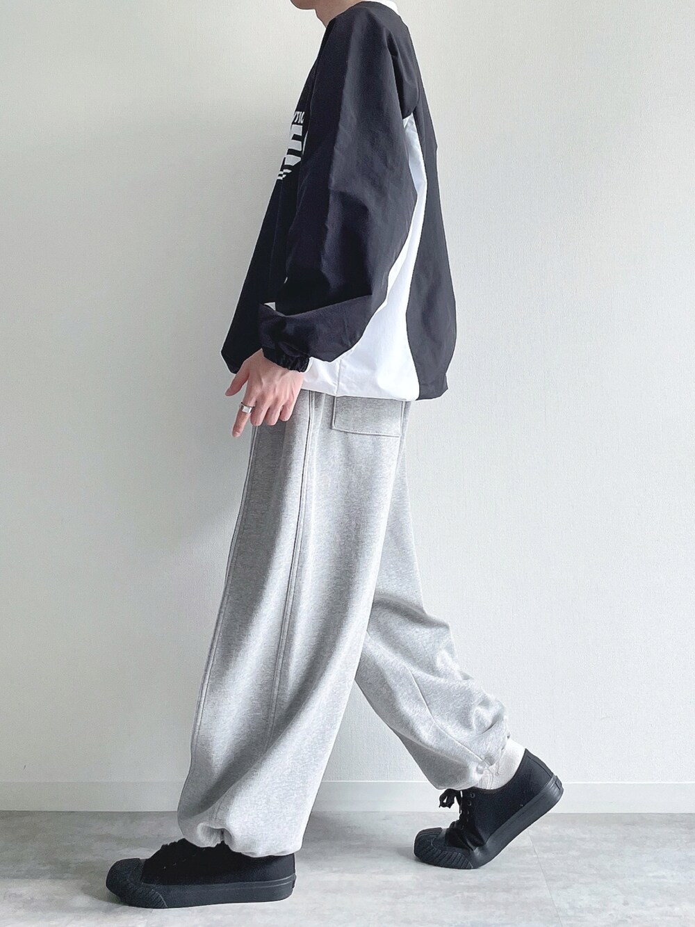 ブラック系のパーカー、グレー系のパンツ、ブラック系のスニーカーを着用したメンズの春コーディネートの3枚目の写真