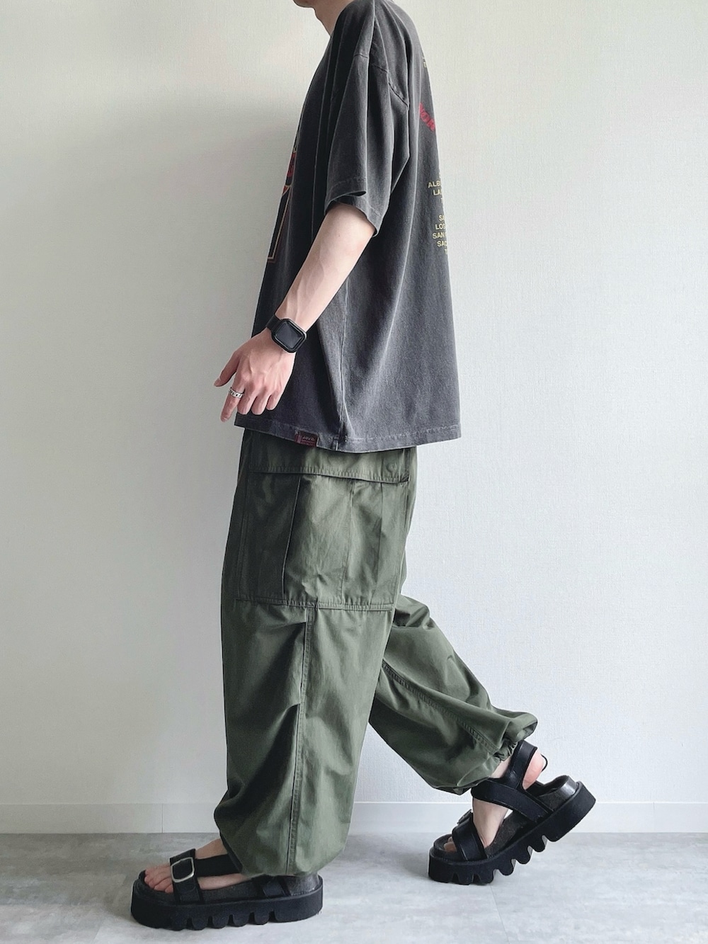 グレー系のTシャツ/カットソー、グリーン系のカーゴパンツ、ブラック系のサンダルを着用したメンズの夏コーディネートの3枚目の写真