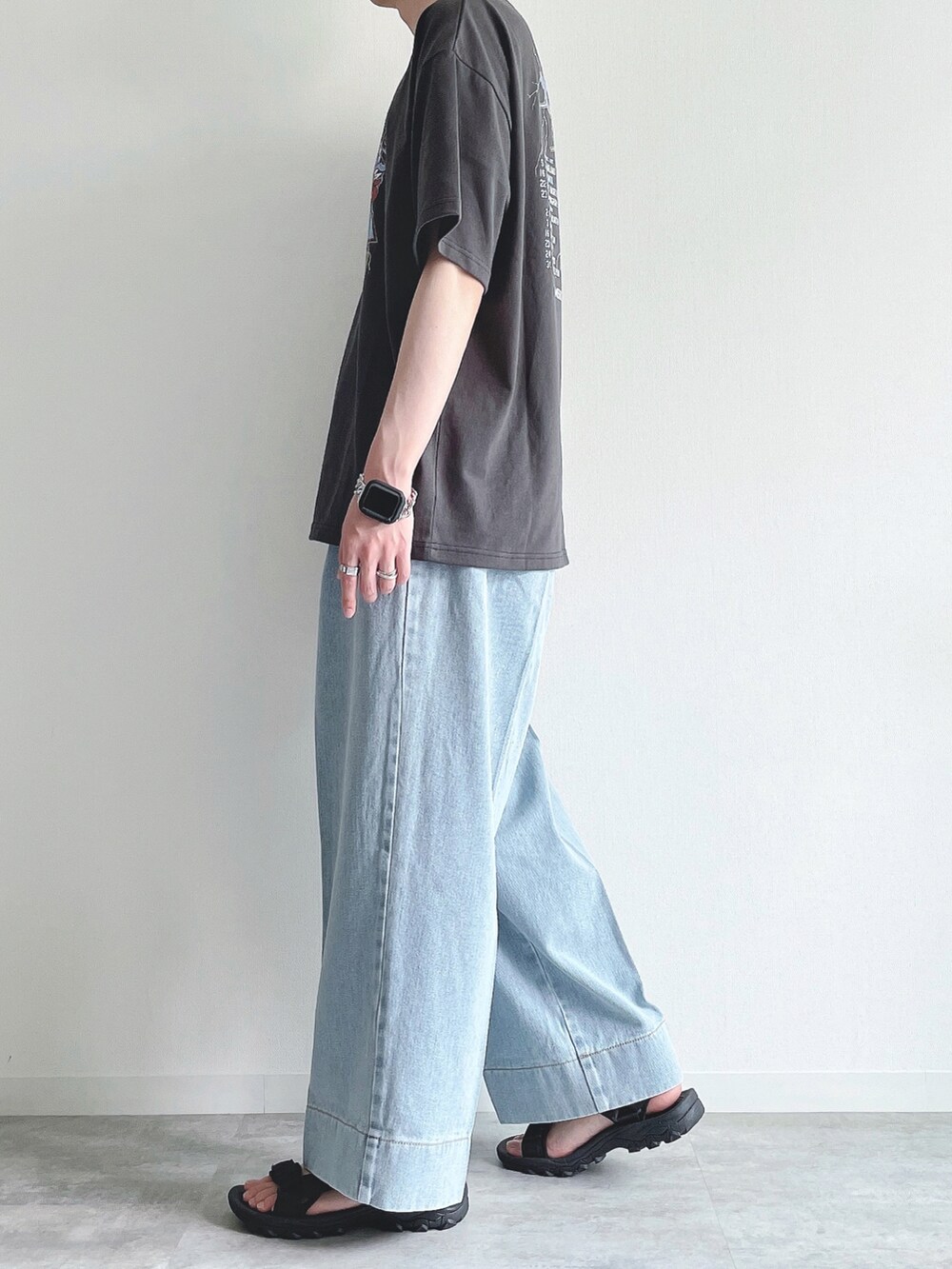 ブラック系のTシャツ/カットソー、ブルー系のデニムパンツ、ブラック系のサンダルを着用したメンズの夏コーディネートの3枚目の写真