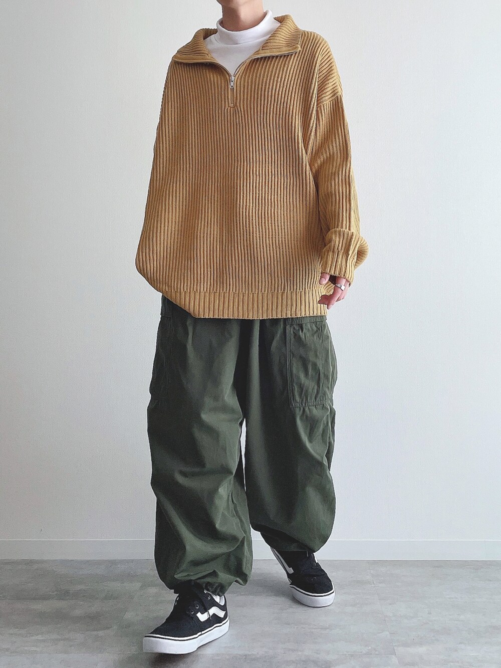 イエロー系のニット/セーター、ホワイト系のTシャツ/カットソー、グリーン系のカーゴパンツを着用したメンズの冬コーディネートの3枚目の写真