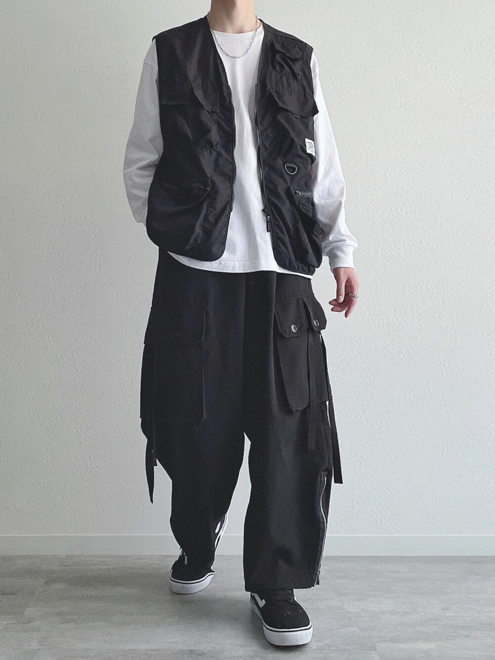 ブラック系のベスト、ホワイト系のTシャツ/カットソー、ブラック系のカーゴパンツを着用したメンズの秋コーディネートの5枚目の写真