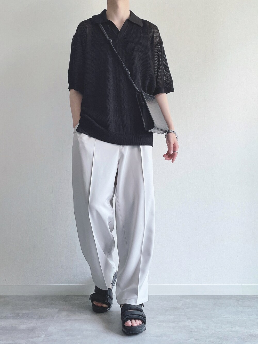 ブラック系のトップス、ホワイト系のスラックス、ブラック系のサンダルを着用したメンズの夏コーディネートの5枚目の写真