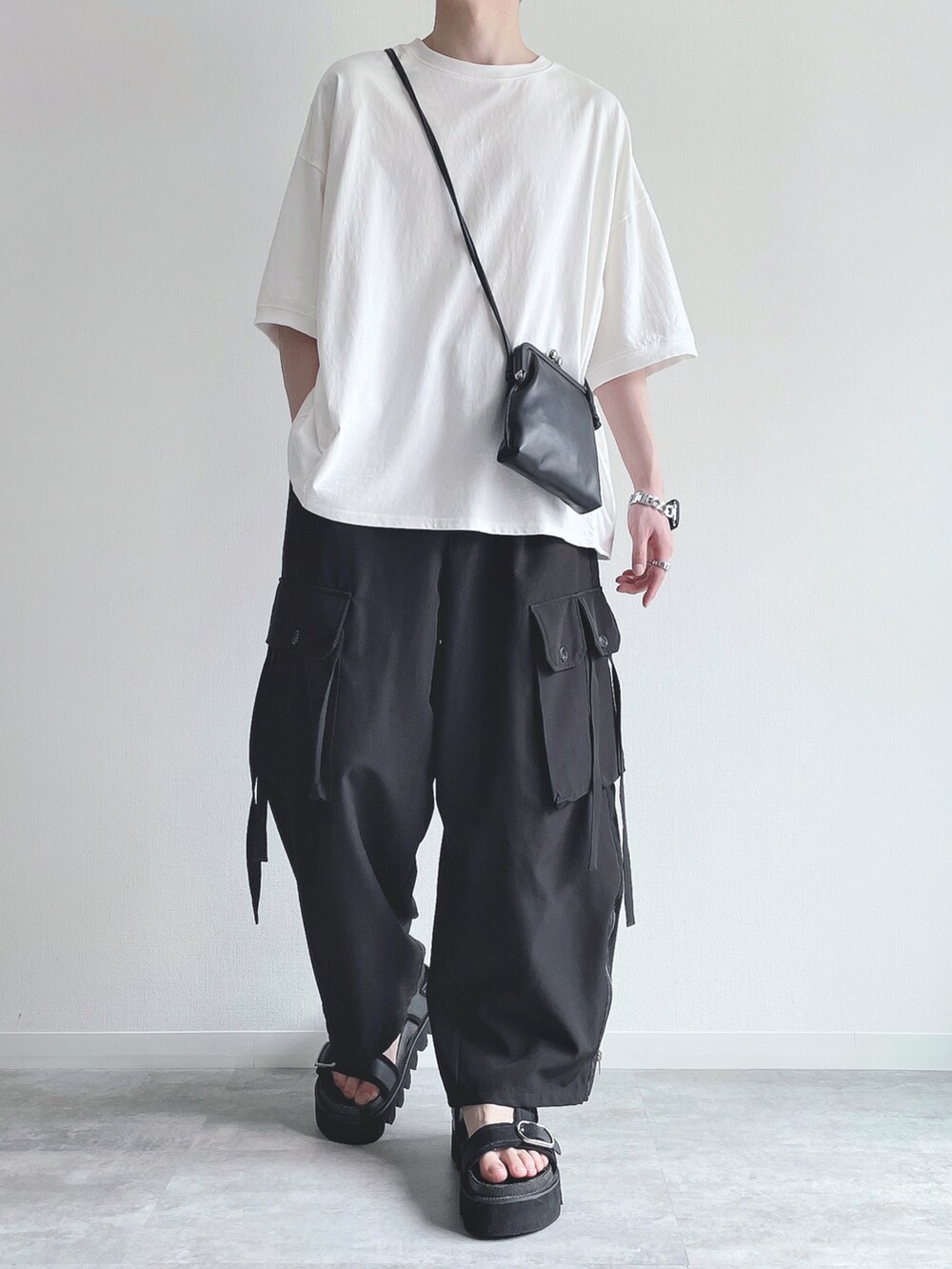ホワイト系のTシャツ/カットソー、ブラック系のカーゴパンツ、ブラック系のサンダルを着用したメンズの春コーディネートの5枚目の写真