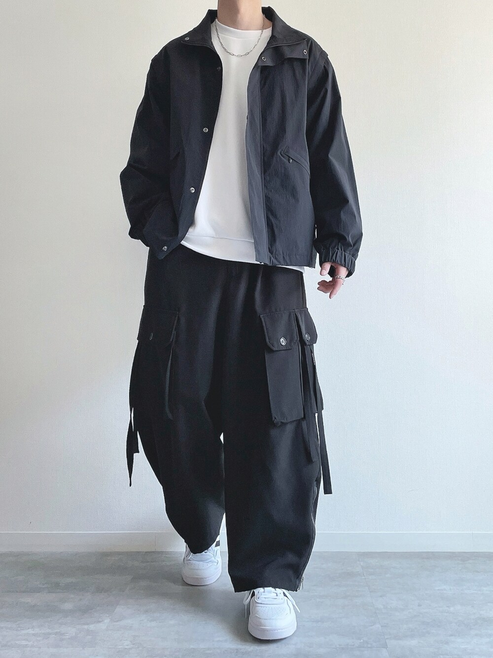 ブラック系のブルゾン、ホワイト系のトップス、ブラック系のカーゴパンツを着用したメンズの冬コーディネートの2枚目の写真
