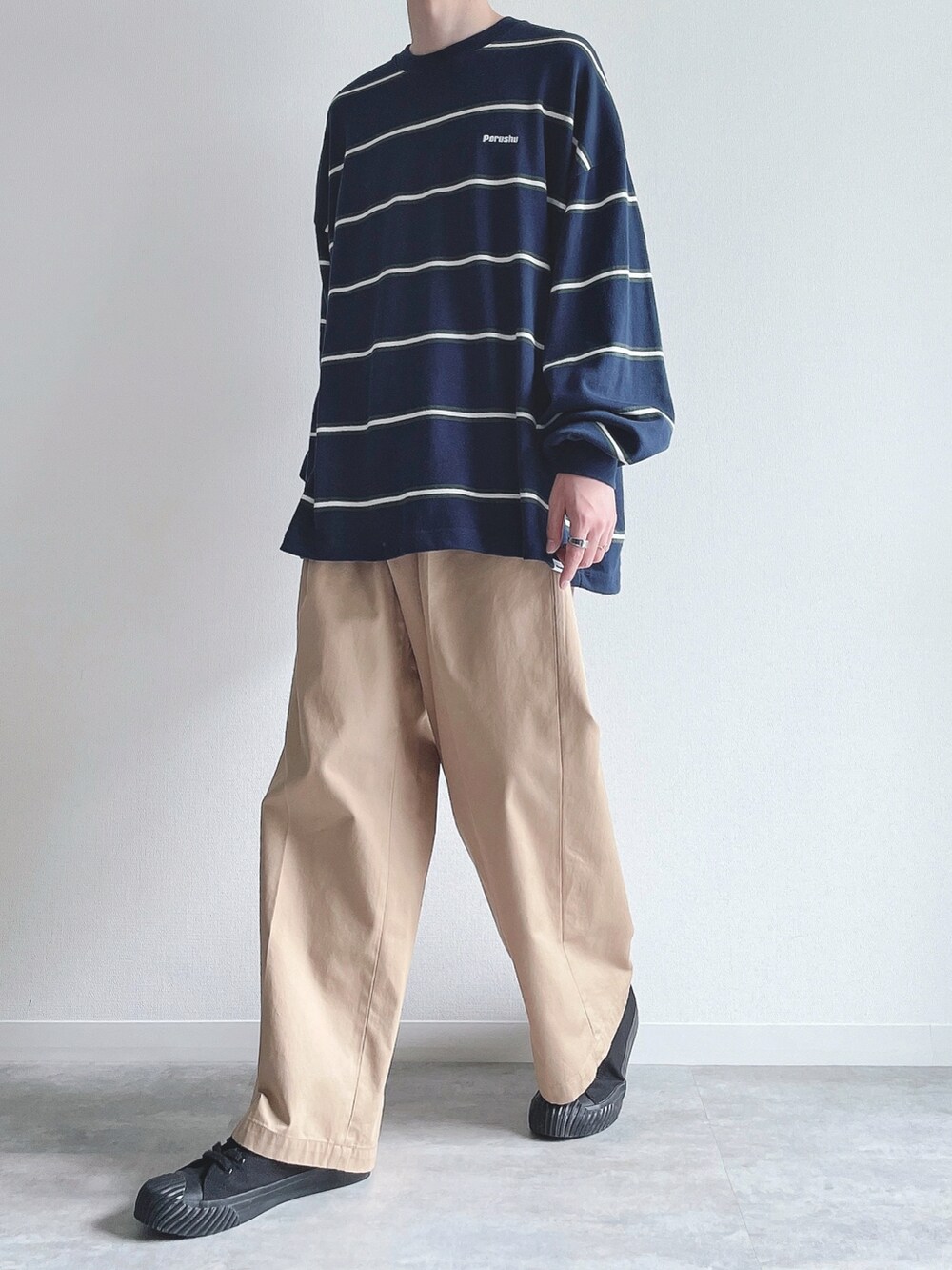 ブルー系のTシャツ/カットソー、ベージュ系のチノパンツ、ブラック系のスニーカーを着用したメンズの秋コーディネートの4枚目の写真