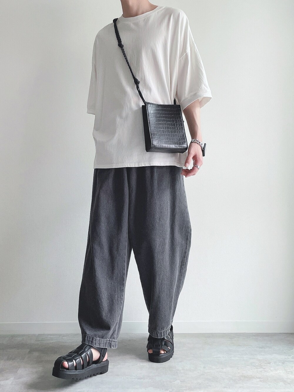 ホワイト系のTシャツ/カットソー、ブラック系のデニムパンツ、ブラック系のサンダルを着用したメンズの夏コーディネートの5枚目の写真