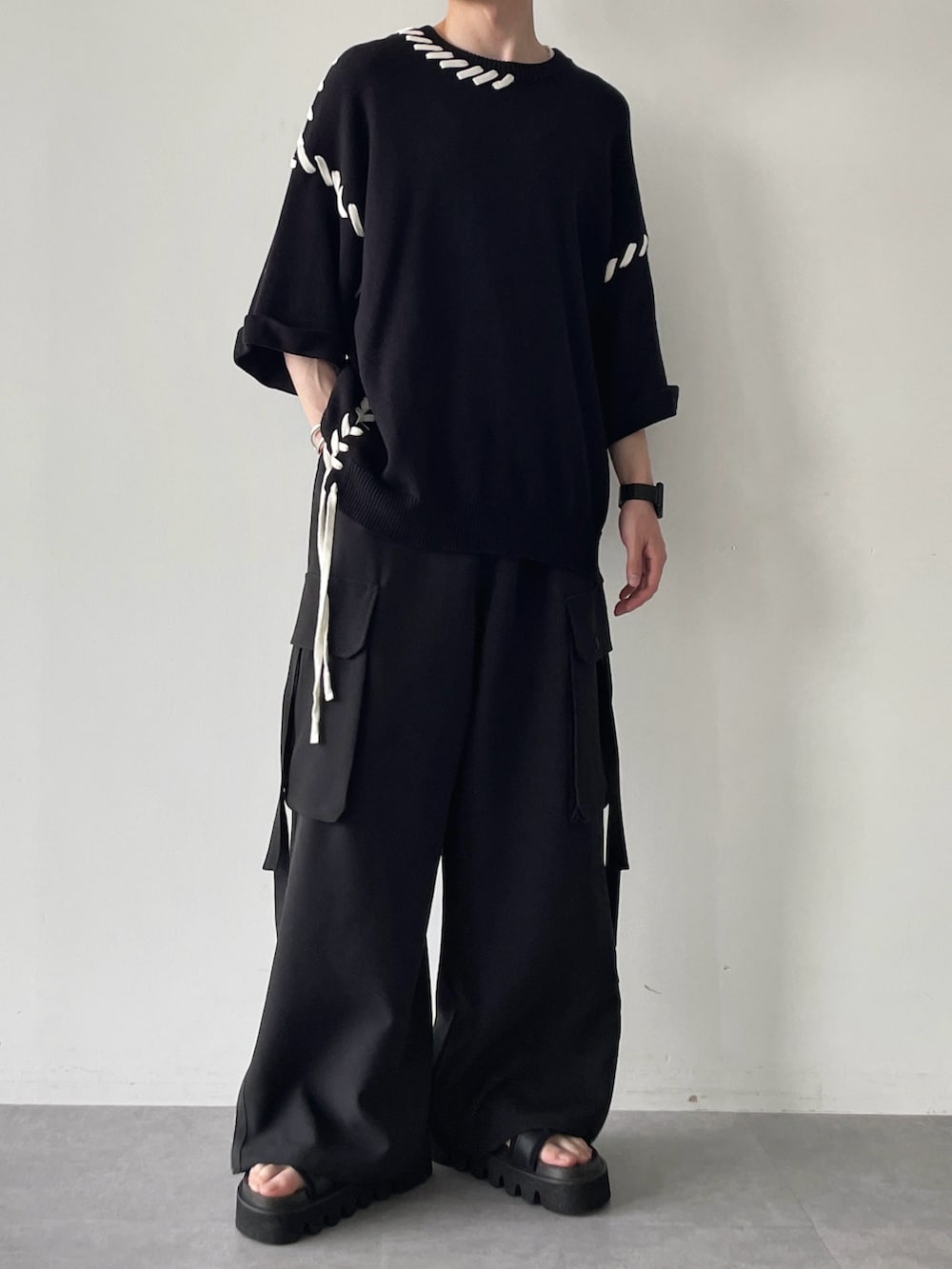 ブラック系のニット/セーター、ブラック系のその他パンツ、ブラック系のサンダルを着用したメンズの春コーディネートの2枚目の写真