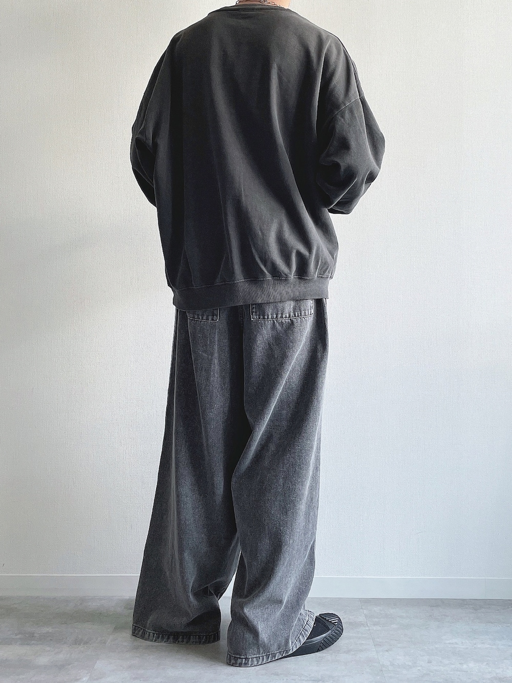 グレー系のスウェット、グレー系のデニムパンツ、ブラック系のスニーカーを着用したメンズの春コーディネートの4枚目の写真