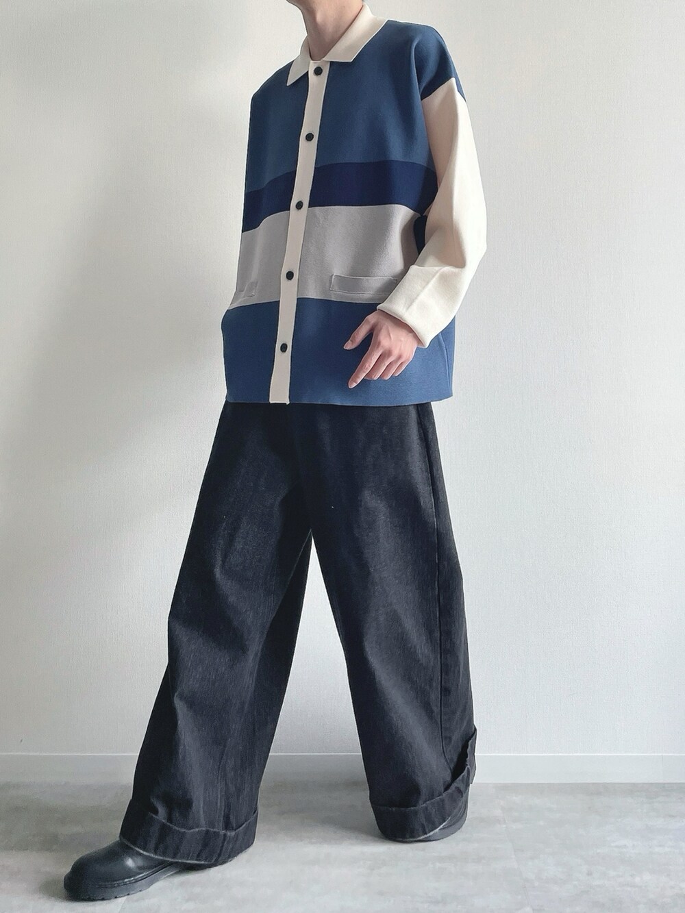 ブルー系のポロシャツ、ブラック系のデニムパンツ、ブラック系のシューズを着用したメンズの秋コーディネートの5枚目の写真