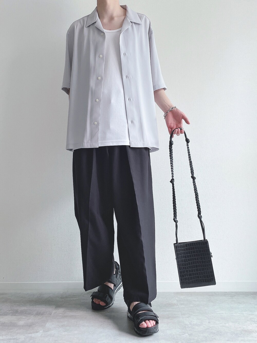 グレー系のトップス、ホワイト系のタンクトップ、ブラック系のスラックスを着用したメンズの夏コーディネートの2枚目の写真