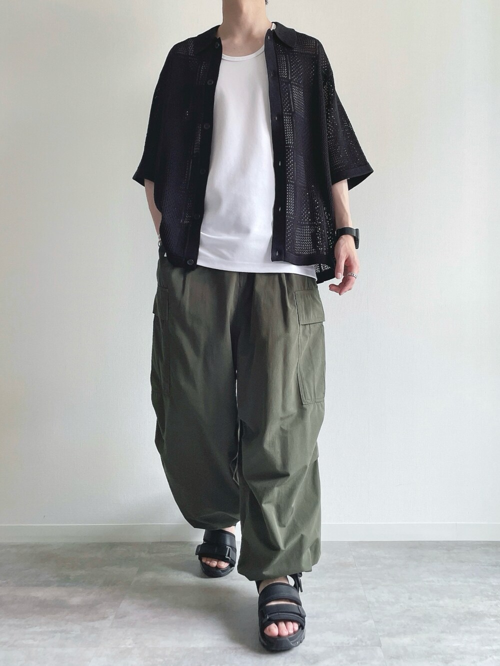ブラック系のトップス、ホワイト系のタンクトップ、グリーン系のカーゴパンツを着用したメンズの春コーディネートの2枚目の写真
