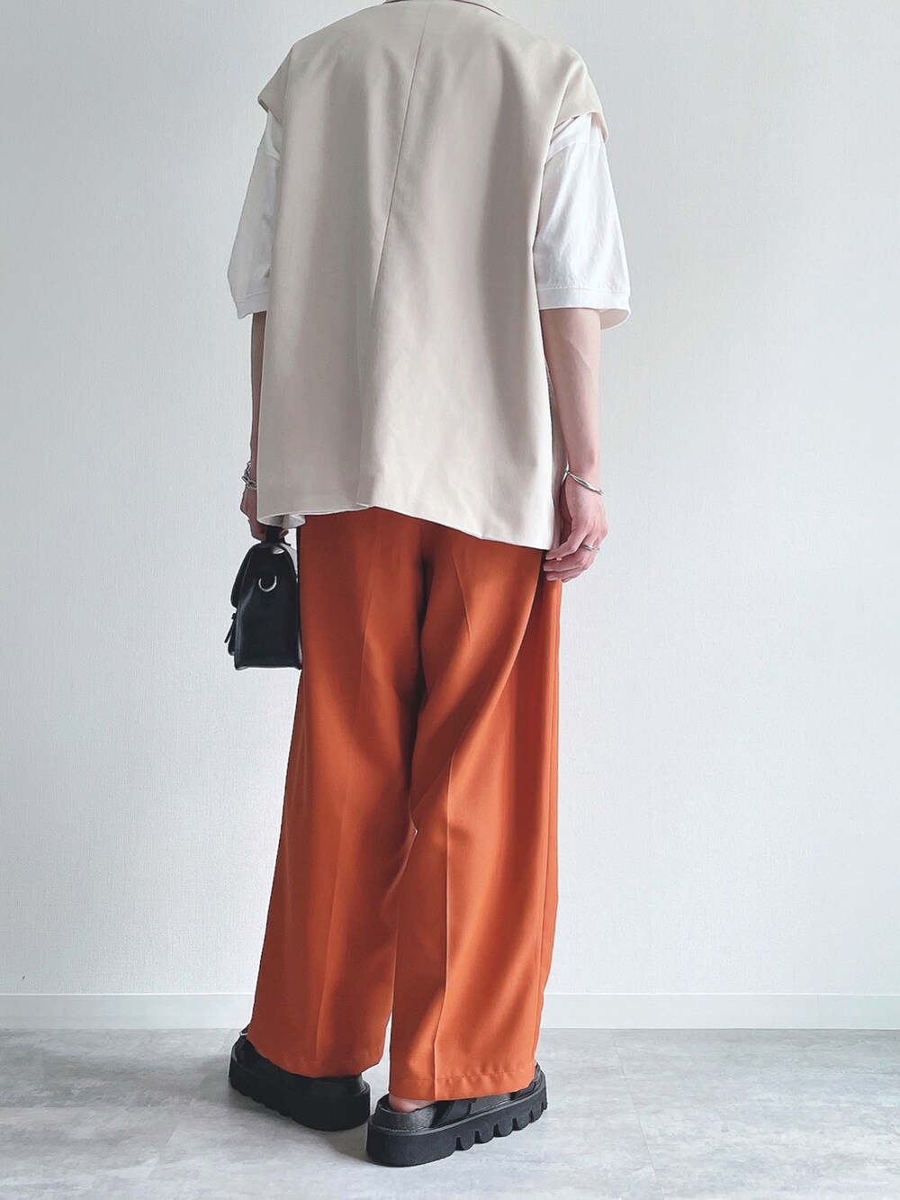 ホワイト系のベスト、ホワイト系のTシャツ/カットソー、オレンジ系のスラックスを着用したメンズの夏コーディネートの3枚目の写真