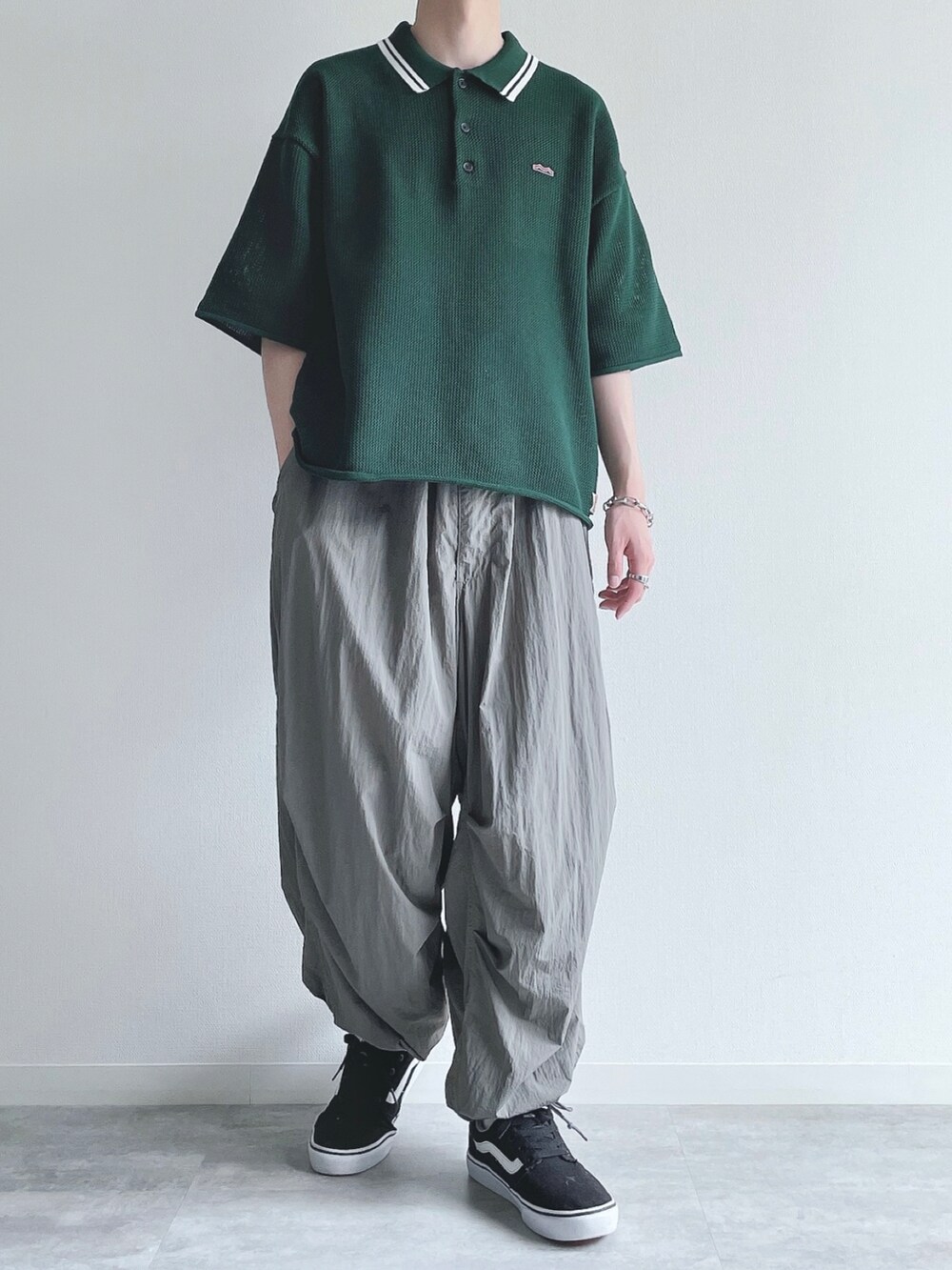 グリーン系のポロシャツ、グレー系のその他パンツ、ブラック系のスニーカーを着用したメンズの夏コーディネートの2枚目の写真