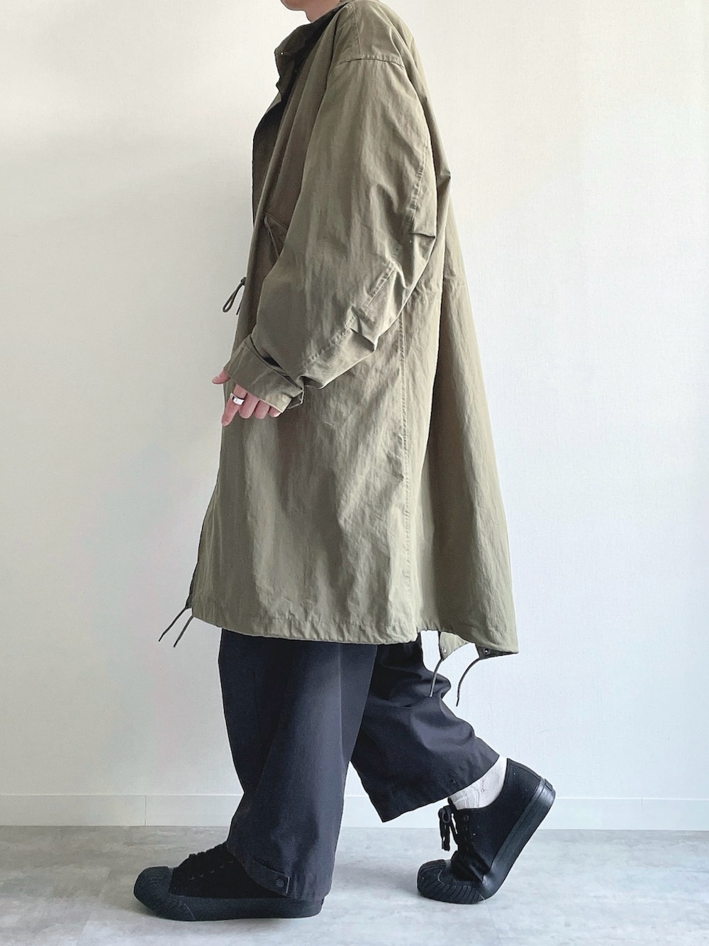 グリーン系のモッズコート、ホワイト系のTシャツ/カットソー、ブラック系のカーゴパンツを着用したメンズの春コーディネートの3枚目の写真